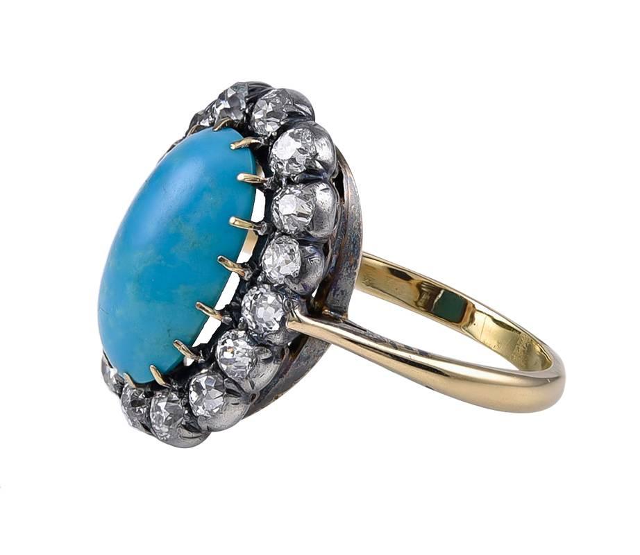 A fine oval Turquoise of good colour which is probably of highly acclaimed Persian origin, safely held by 16 Gold prongs and with a surround of 16 Old European Mine Cut Diamonds, about 1 carat 60 in total, all Silver set on Gold with a yellow Gold