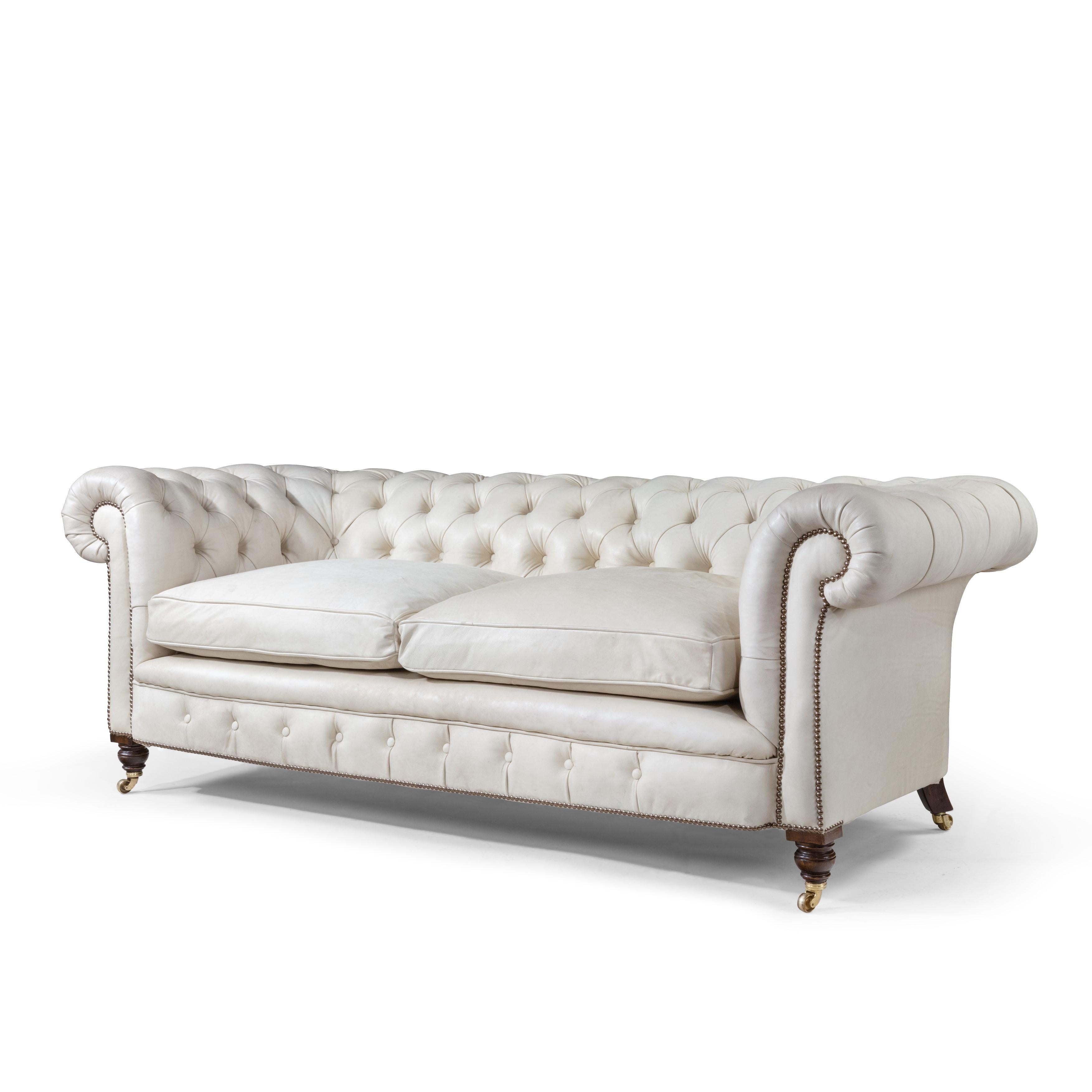 A late Victorian two-seat mahogany Chesterfield sofa, of typical form with rolled arms and two-seat cushions, on the original castors, reupholstered in natural leather (to be colored on request). English, circa 1890.
   