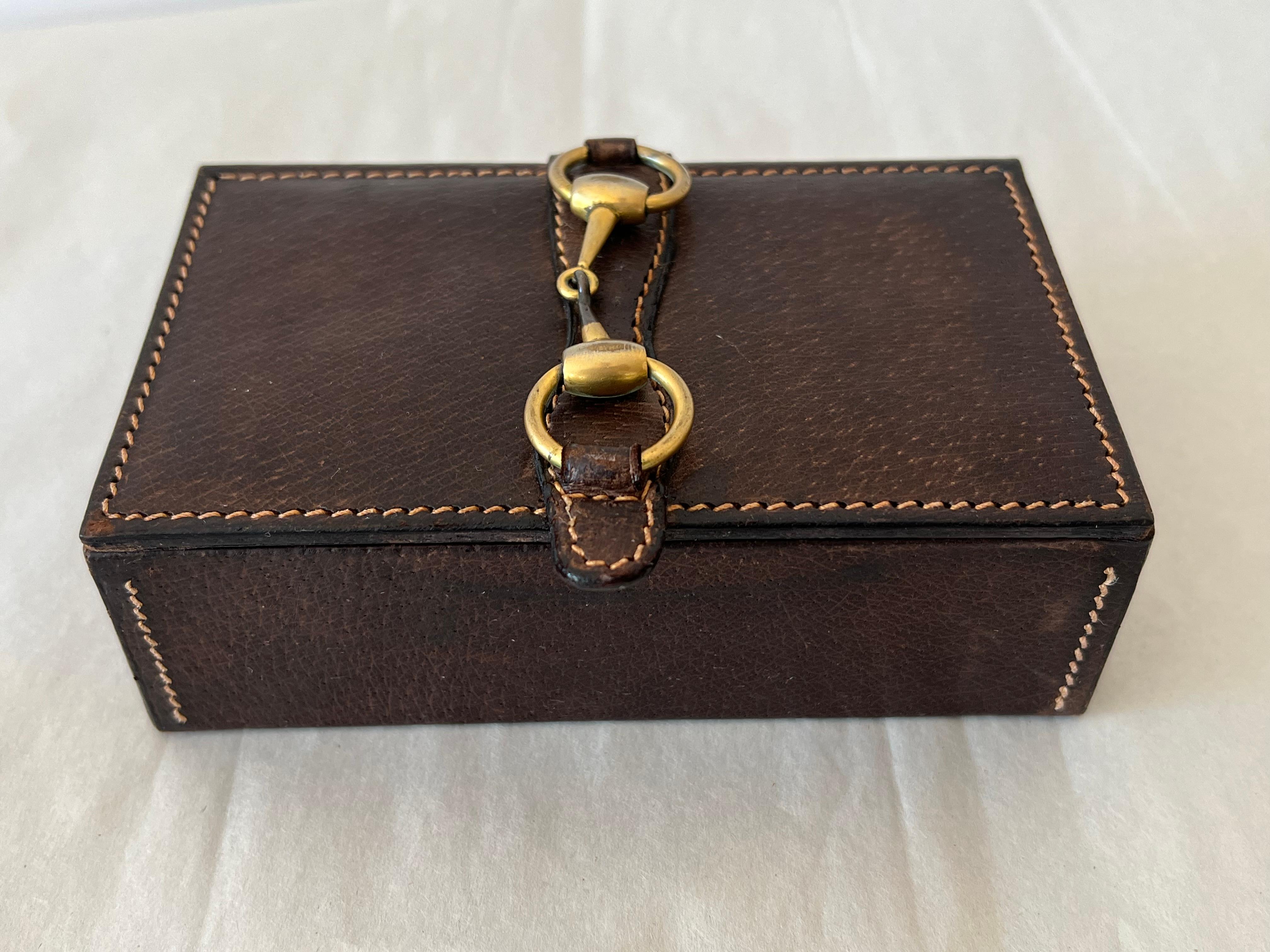 Un affascinante portagioie di Gucci. Pelle marrone scuro con decorazioni in ottone a forma di morsetto. Bellissima cucitura, fatta a mano e firmata sotto.