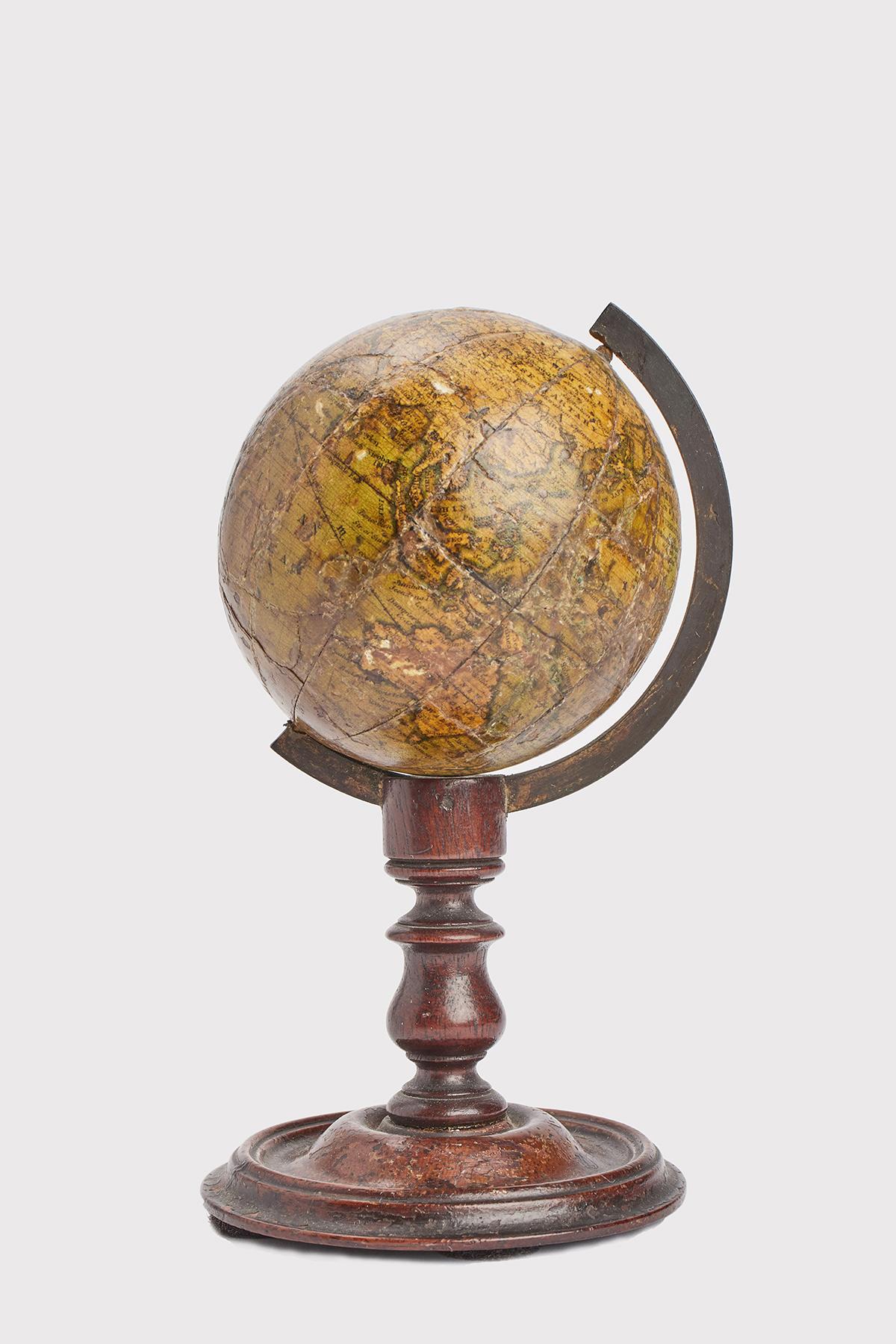 Over a round foot that rise with a central element with moved profile is connected the brass half meridian, which holds at the ends the metal axe of the little globe. The base is made out of dark brown Mahogany wood. The globe is made out of