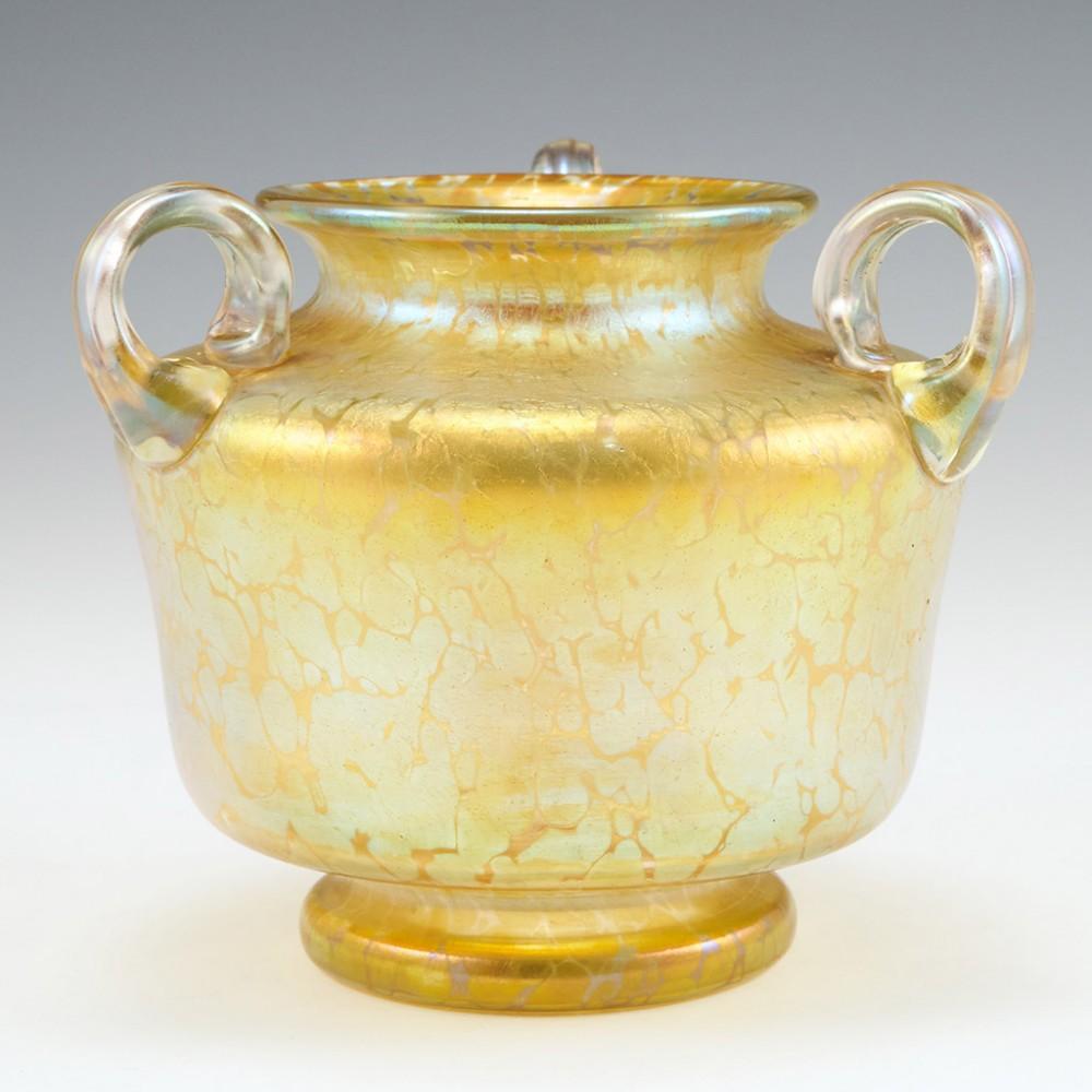 A Loetz Witwe Candia Papillon Vase, c1900

Additional information:
Date : c1900
Origin : Klostermuhle, Bohemia 
Bowl Features : A three handled clear vase with yellow gold Candia iridescent finish. Ribbed handles
Marks : Polished pontil
Type : Lead