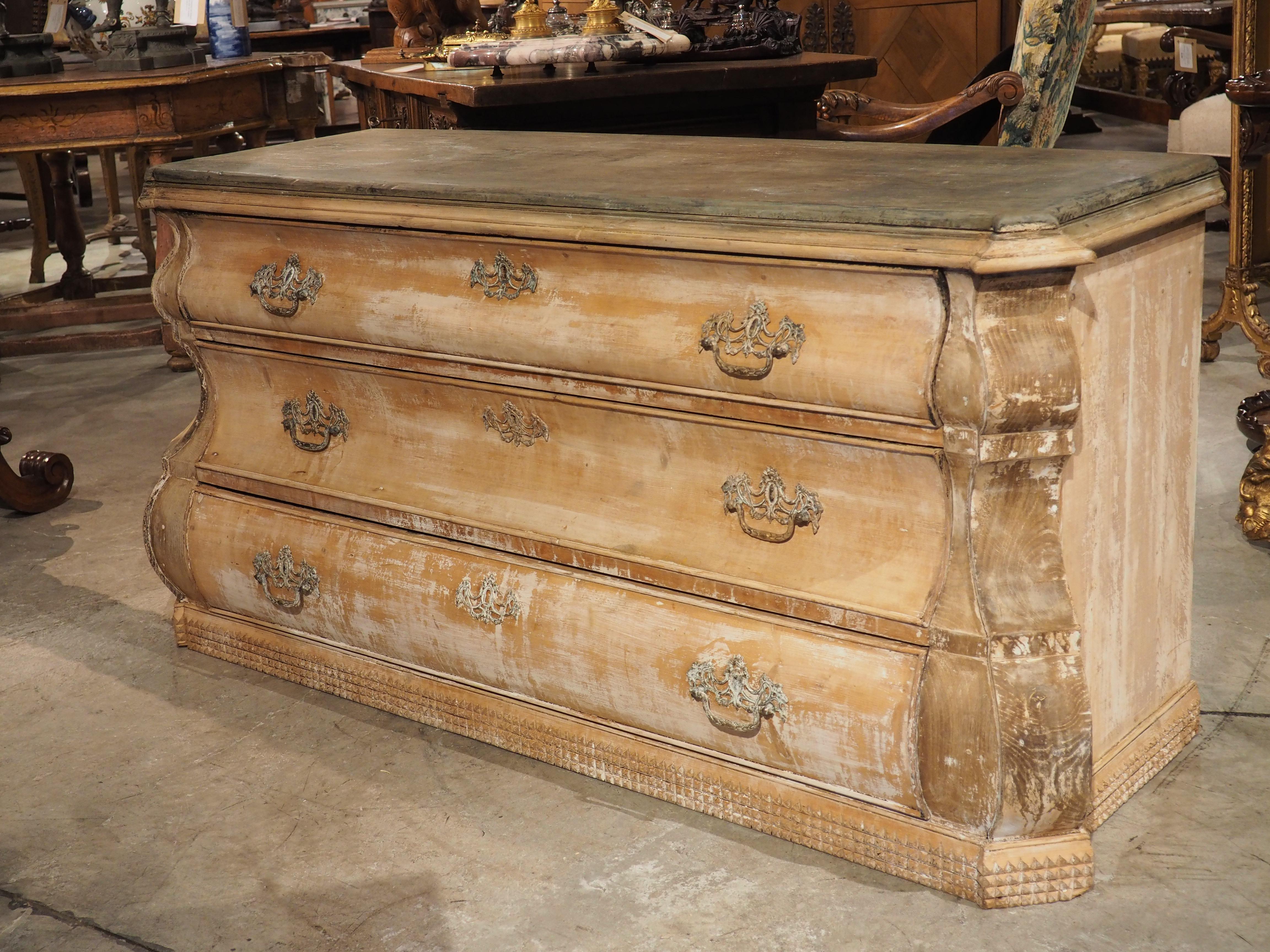 This exquisite Dutch chest of drawers, with its unique shape and finish , measures nearly 5 1/2 feet long. The chest features a bombe front with protruding pilasters that add a sense of grandeur to its design. The middle drawer boasts a concave