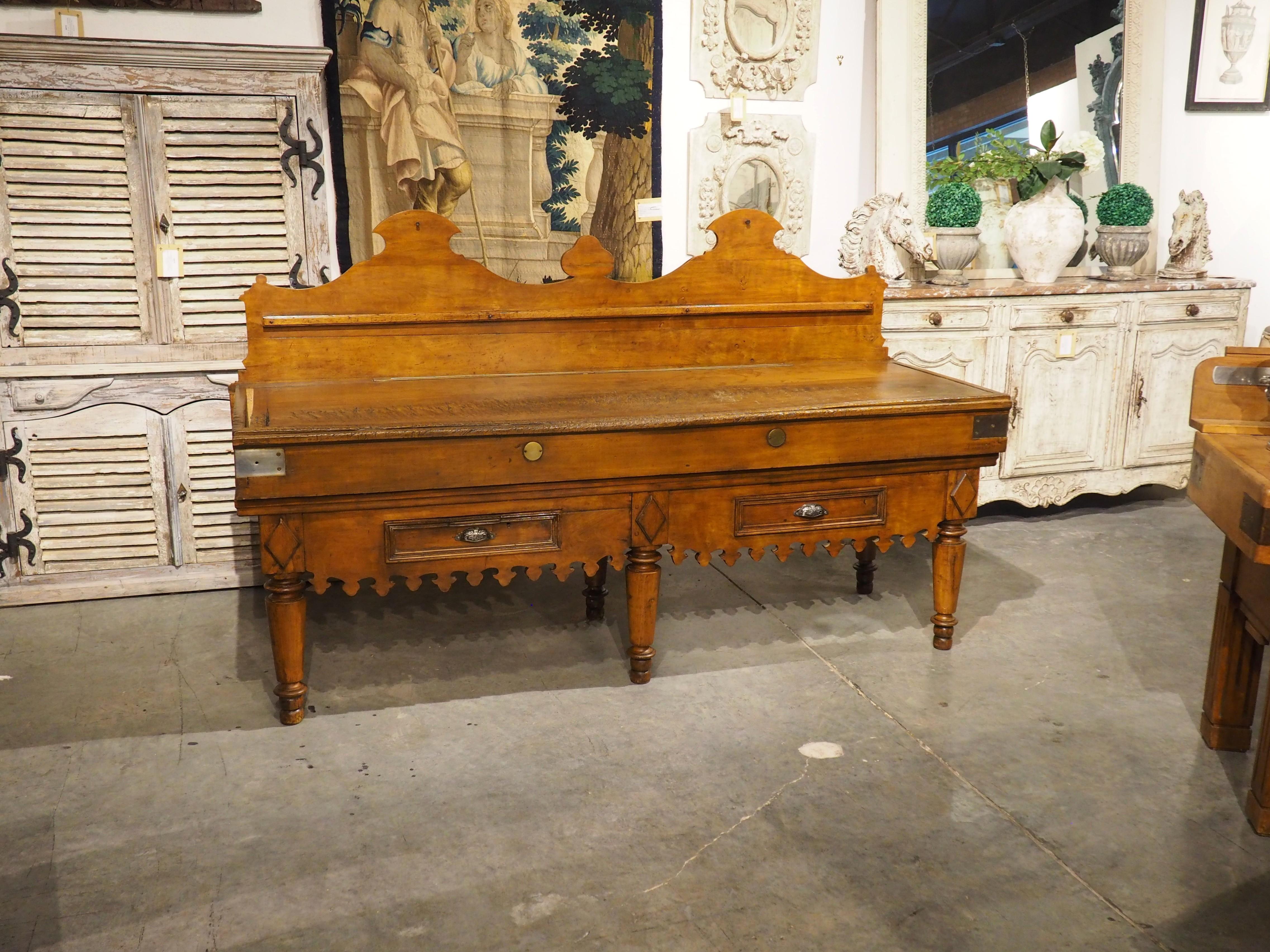 Known in France as a billot de boucher, this long, double butcher block dates to circa 1900. This is a stunning example with a crenellated apron and high rising back wall that softens the overall linear composition. Supported by six tapering spindle