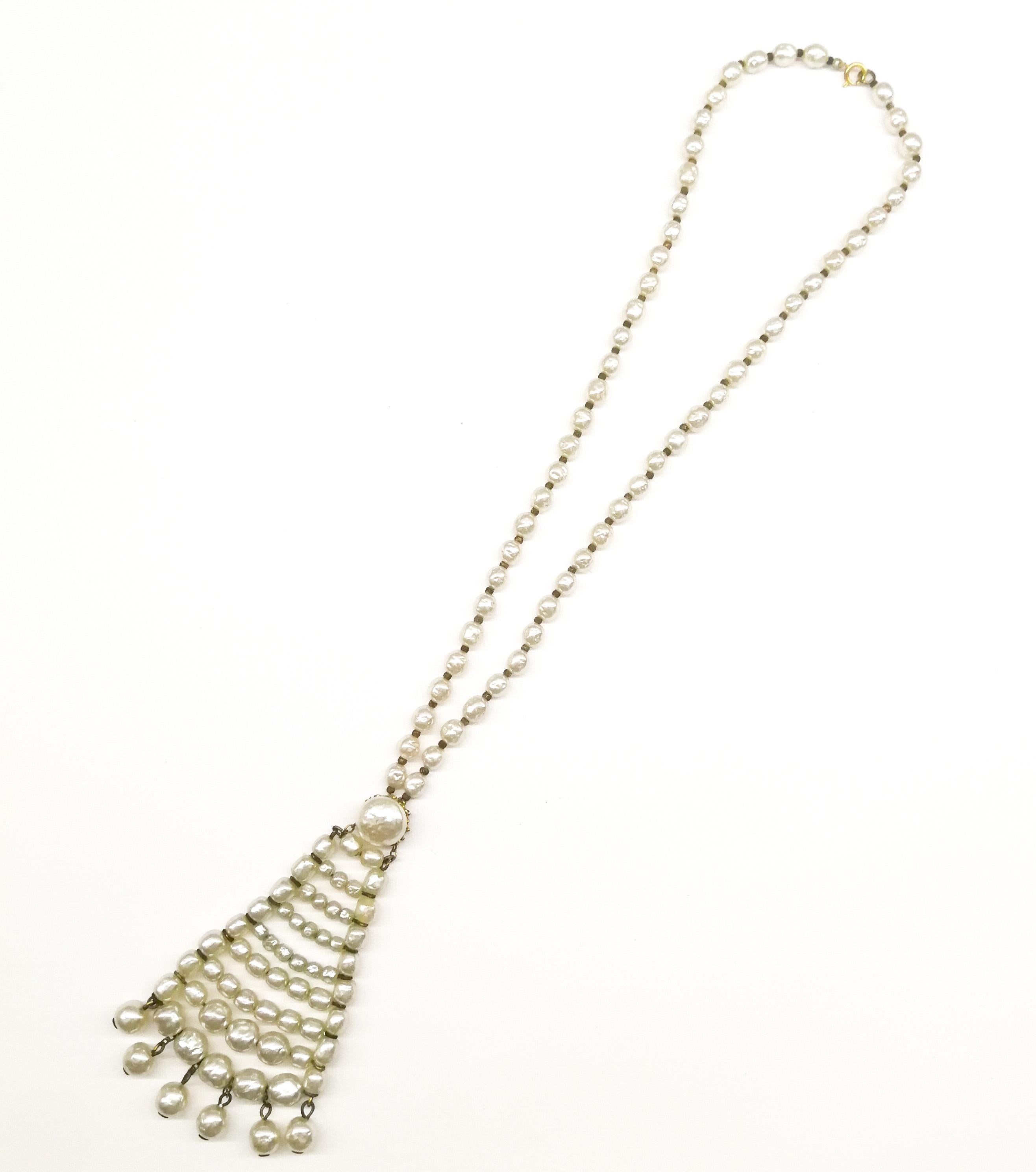 A long baroque pearl sautoir or pendant necklace, from the 1960s, made from signature Miriam Haskell glass pearls, filled with wax, to give weight, dipped in a mother of pearl solution. A single row of pearls lead down to a structured triangular