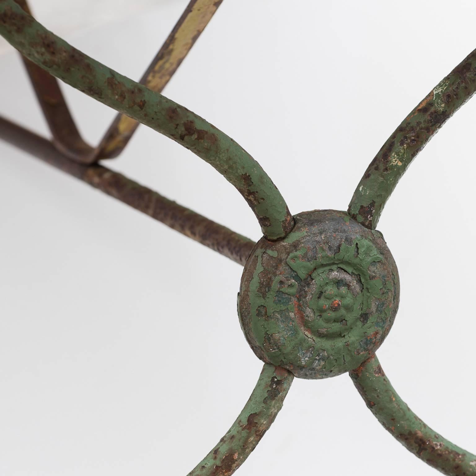 This table is quite unusual with a wrought iron base consisting of four legs with centre medallions, and feet that are typical of the late 19th century in France. It is marked “Brahic Nimes” and was made in that village in Provence. The green paint