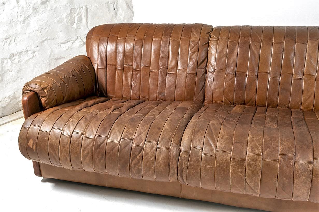 A 1970s mid century patchwork leather sofa of the highest quality with superb supple leather in a warm pecan brown colour. A long 3 seater, will sit 4, beautiful soft rollover armrests with wood feature to the ends. Low back with rollover leather