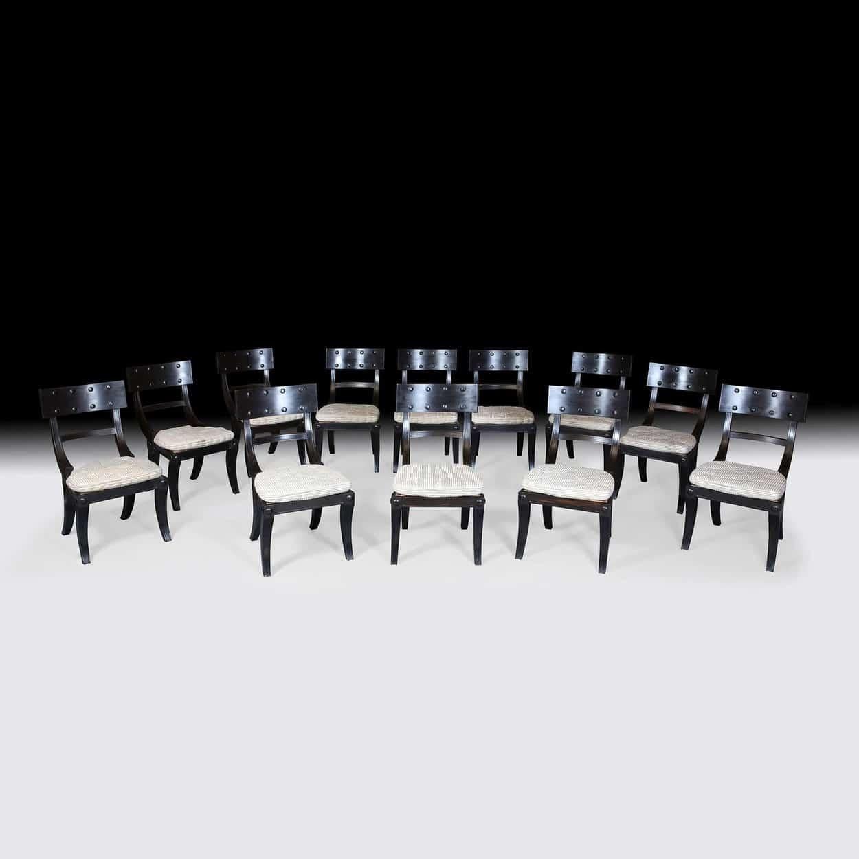 A long set of 12 solid ebony klismos dining chairs, each with handmade horsehair squab cushions.
Contemporary production

Measures: Seat height includes 2inch horse hair cushion, 18 inches
Seat width 18.5in
Height of back 35in.

  