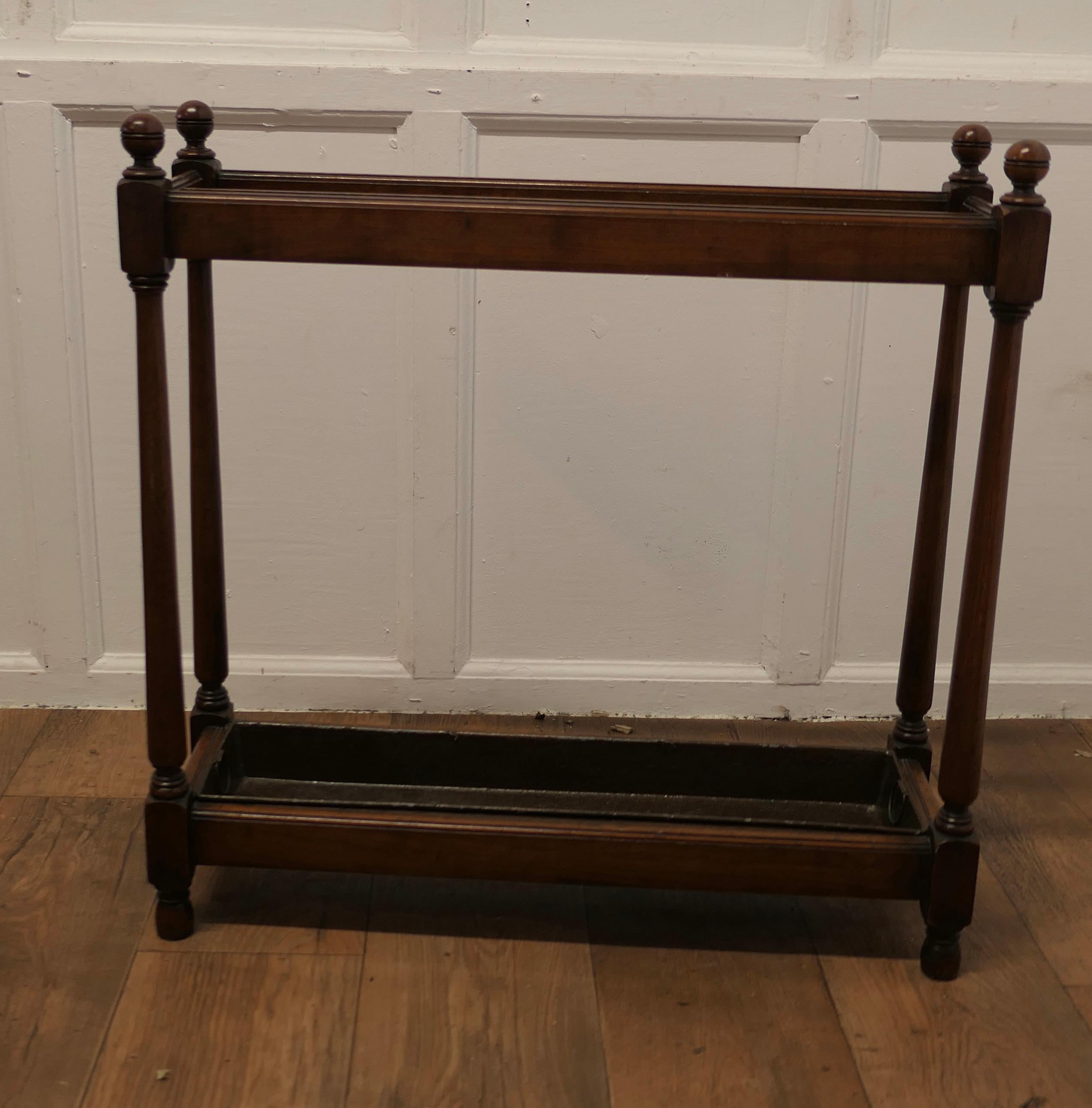 A Long Walnut Stick Stand or Umbrella Stand

This is a good Umbrella stand, it is made in walnut with turned spindles and a long metal drip tray 
The top is  divided into 12 sections and it will hold a lot of Walking Sticks,Umbrellas, Tennis Rackets
