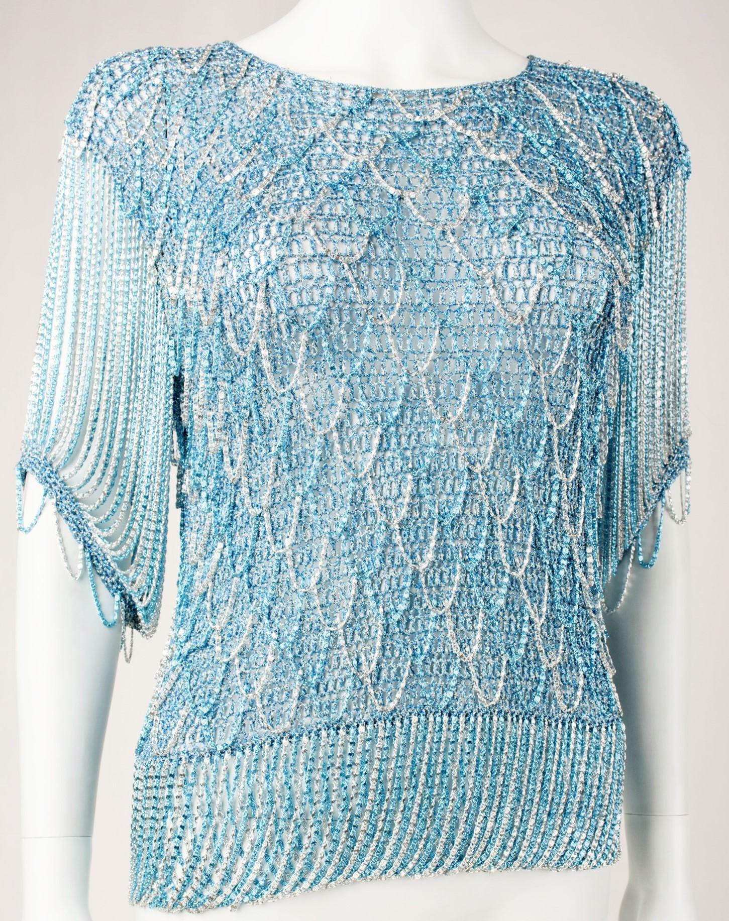Circa 1970
France

Top by Loris Azzaro in Lurex knit and chain blue and silver dating from the period of the Parisian Music-Hall in the 1970s. Top with boat neckline closed behind by a snap. Knitted lurex bottom, embroidered with metallic chains