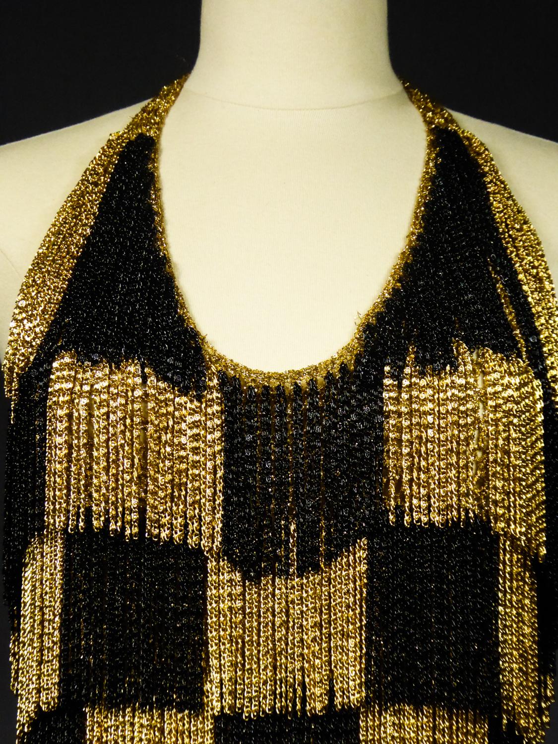 Circa 1970
France

Loris Azzaro backless top in gold Lurex knitwear and small gold and black chains from the 1970s and the Parisian Music Hall period. Knotting of the top with Lurex ties behind the neck allowing a large plunging neckline for the