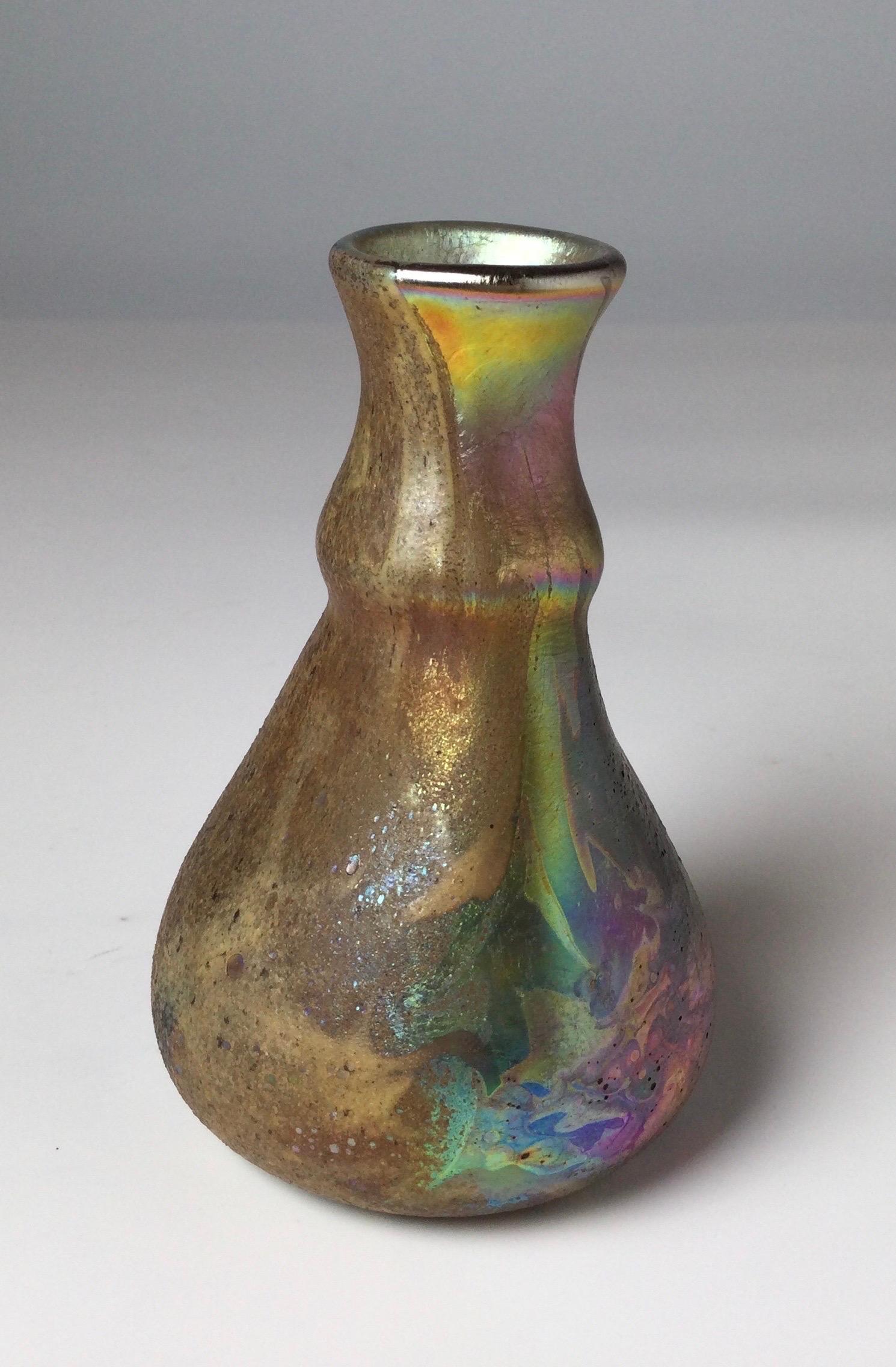 A Louis comfort Tiffany Cypriot lava glass vase of irregular tapering form with swelled neck and flared lip. The glass in shades of blue, pink, gold iridescence with spotted areas. Unsigned, Provenance Mr. and Mrs. George Schrim.