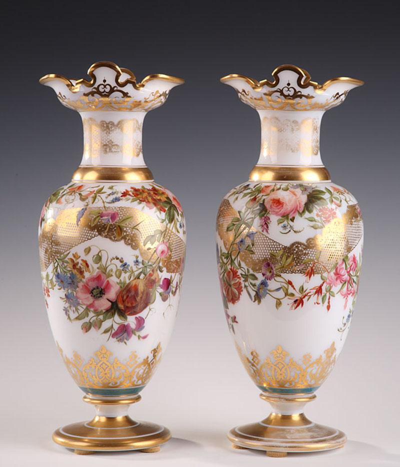 An enamel opaline baluster-shaped pair of vases decorated with polychromatic flowers in lobed cartridges on light blue background hightened with white and gilded rinceau. The base and collar are underlined with gilded stripes. Light wear to the