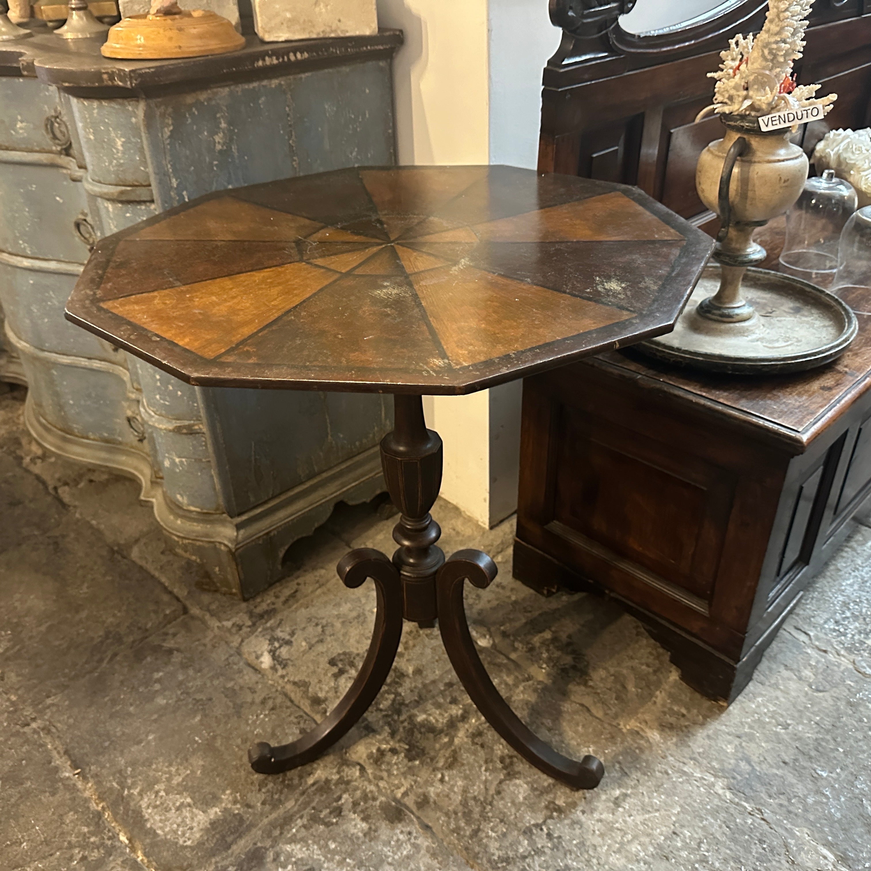 This is a Louis Philippe Sicilian octagonal tilt-top table crafted in the 19th century. It features a distinct octagonal tabletop with a geometric inlay design, combining warm wood tones in a sunburst or pie-slice pattern. The top can tilt