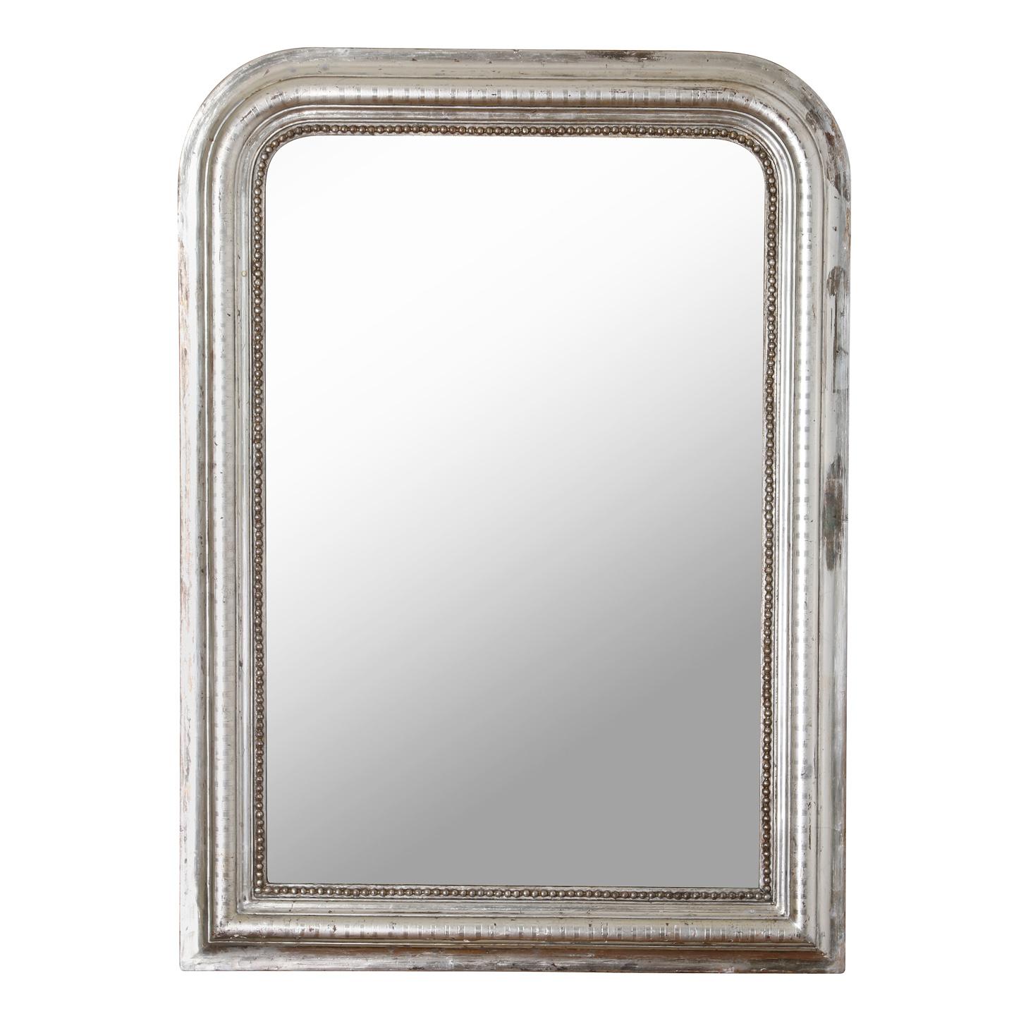 A Louis-Philippe mirror is often the perfect finishing touch in a room. This silvered wood mirror has a straight bottom with curved corners at the top, a form characteristic of the Louis Philippe style.  The frame its decorated with a geometric