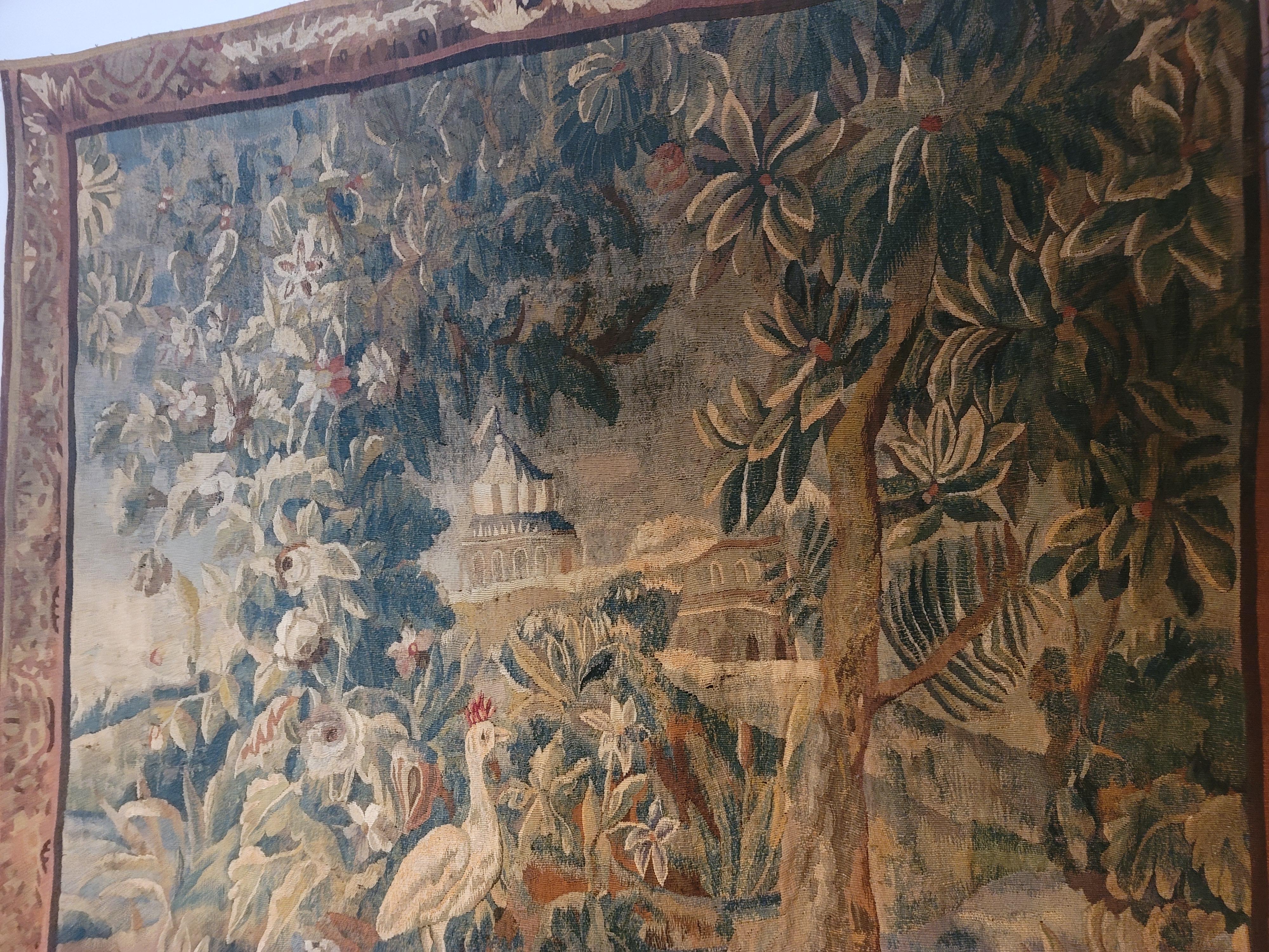 This magnificent tapestry, woven in wools and silks, showcases a captivating wooded lakeside landscape with birds taking center stage. The brown and cream slips, along with a floral and foliage border, beautifully complement the intricate design.