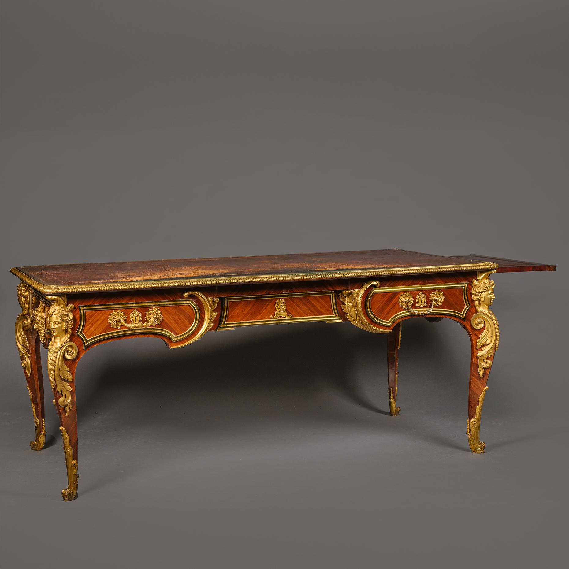 A Louis XIV Style Gilt-Bronze Mounted Mahogany Bureau Plat, By Cueunières, Paris. After the Model by Charles Cressent. 

Stamped to underside 'L. CUEUNIERES JNE / ÉBÉNISTE'

The original gilt-embossed tan leather top surround by an oval moulded