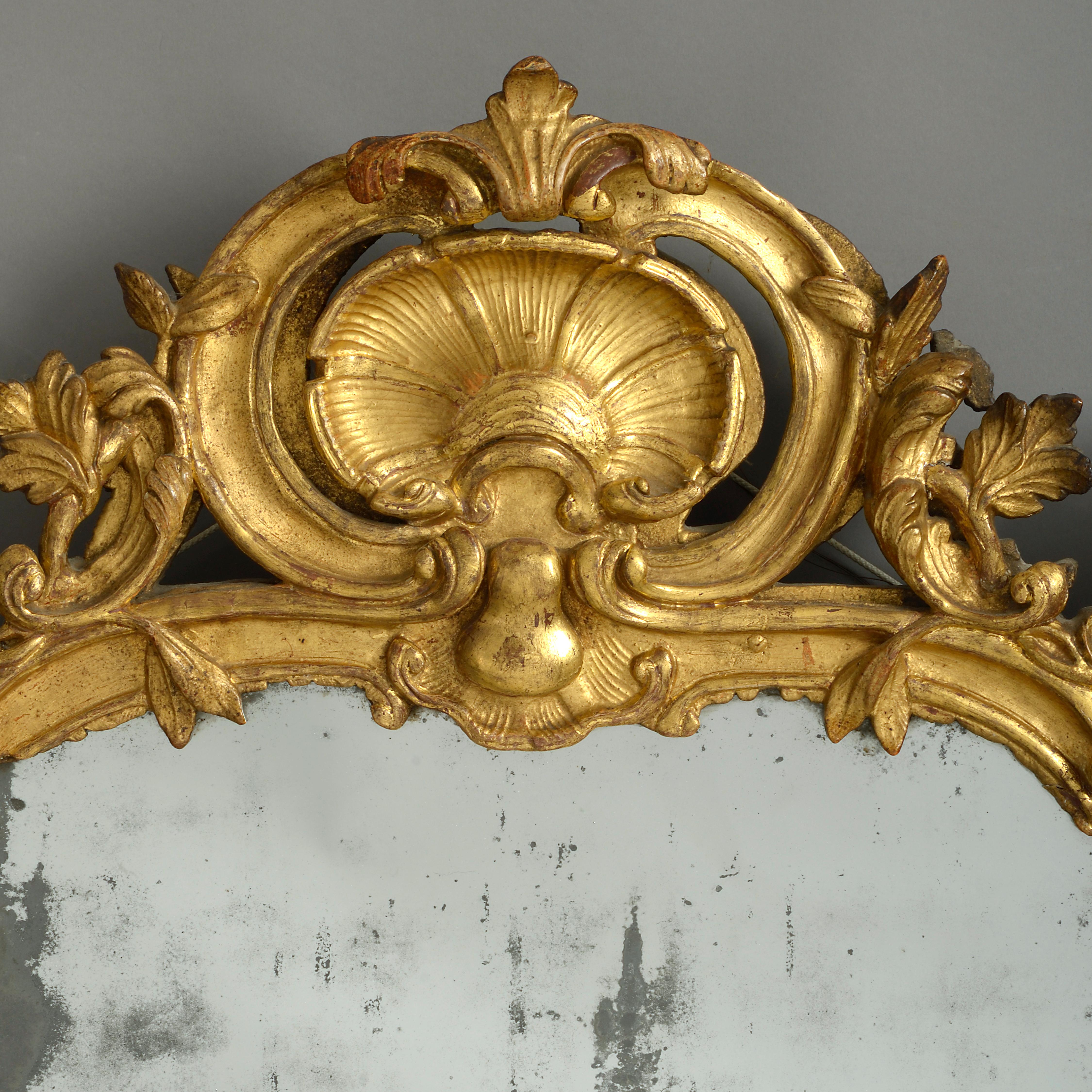 A fine mid-18th century Louis XV Period carved giltwood mirror in the Rococo manner and retaining the original mercury glass plate.