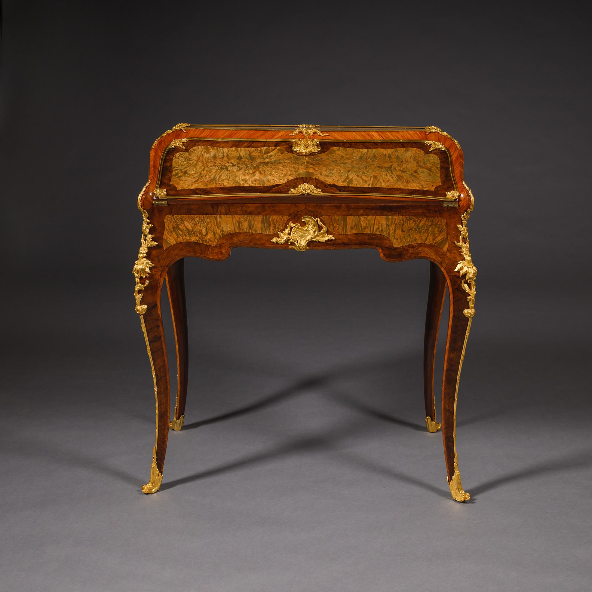Of slightly bombé form and decorated à quatre faces. The hinged slope revealing a fitted interior. Mounted with channelled encadrements and rocaille clasps. The cabriole legs headed by pierced foliate chutes. 

England, Circa 1840/50.

The design of