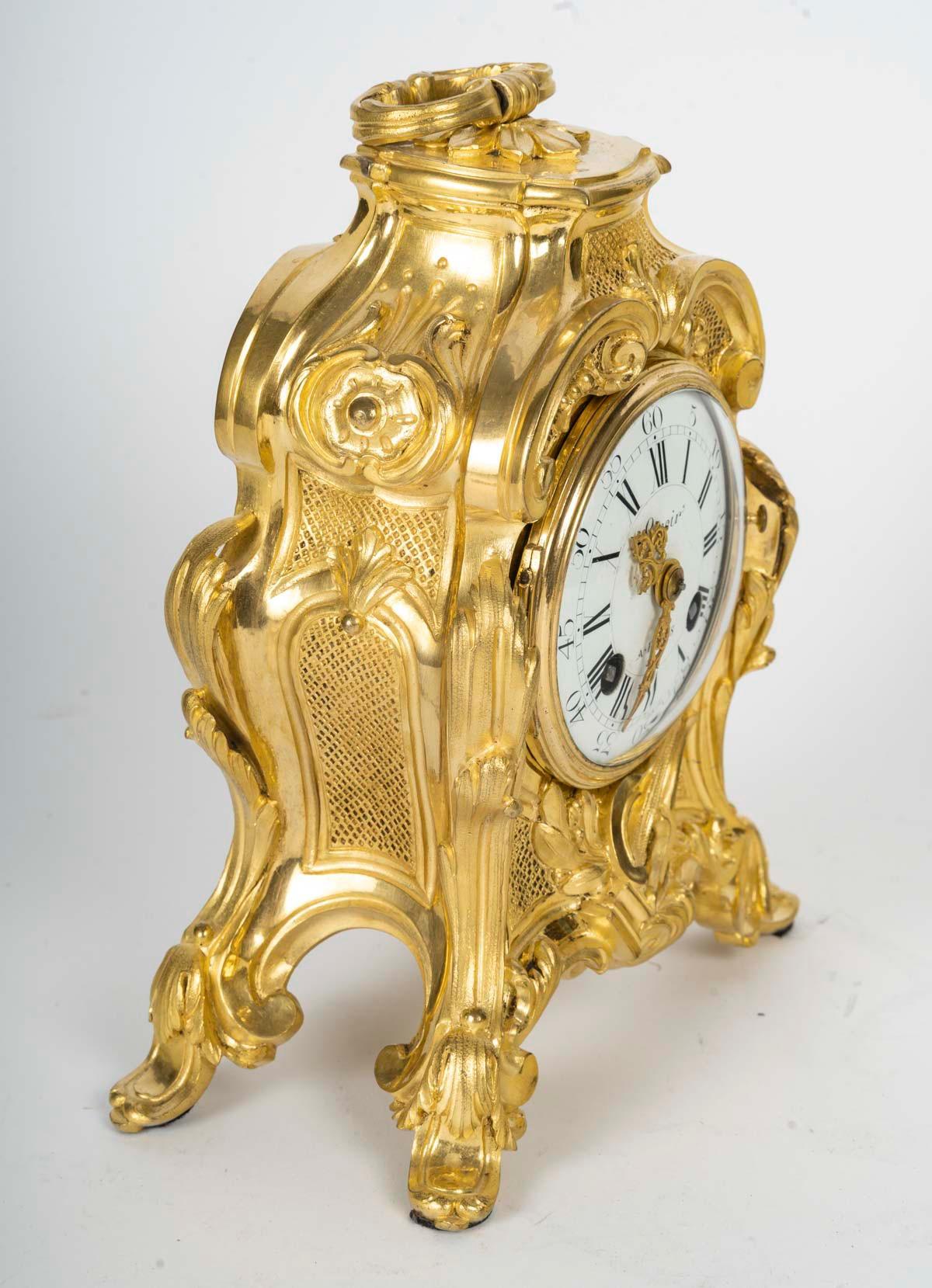 Reloj de sobremesa Travelling Cartel de bronce cincelado y dorado
Decoración rocalla de roleos, hojas de acanto y lira
Esfera esmaltada firmada Lenoir en Paris
Placa de mecanismo nº 13287 y sello del relojero
Estilo Luis XV
Circa 1875
Dorado