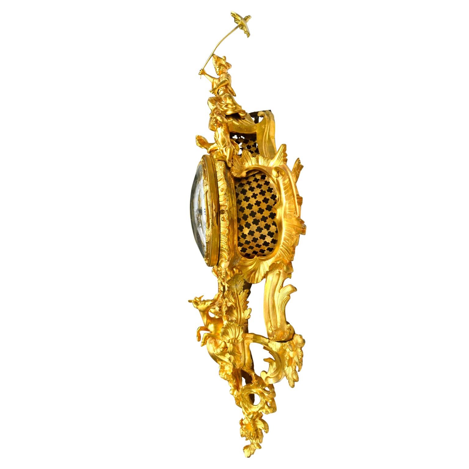 A fine gilded bronze French cartel (wall clock) in the Louis XV rococo style. A Chinese figure sits atop the clock case holding an umbrella aloft, a young child to one side of her, a seated dog on the other. Rocaille work, shells, flowers, sun's