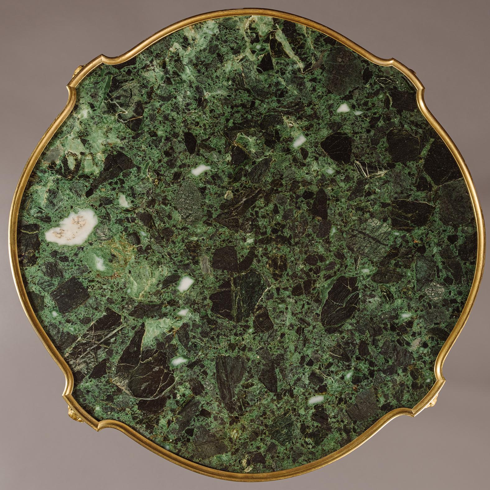 Gueridon intarsiato in bronzo dorato con piano in marmo, stile Luigi XV, di Emmanuel Zwiener.

Questo tavolo gueridon o occasionale ha un piano in marmo verde. Il fregio presenta rami fioriti intarsiati. Gli angoli sono incastonati con chiusure
