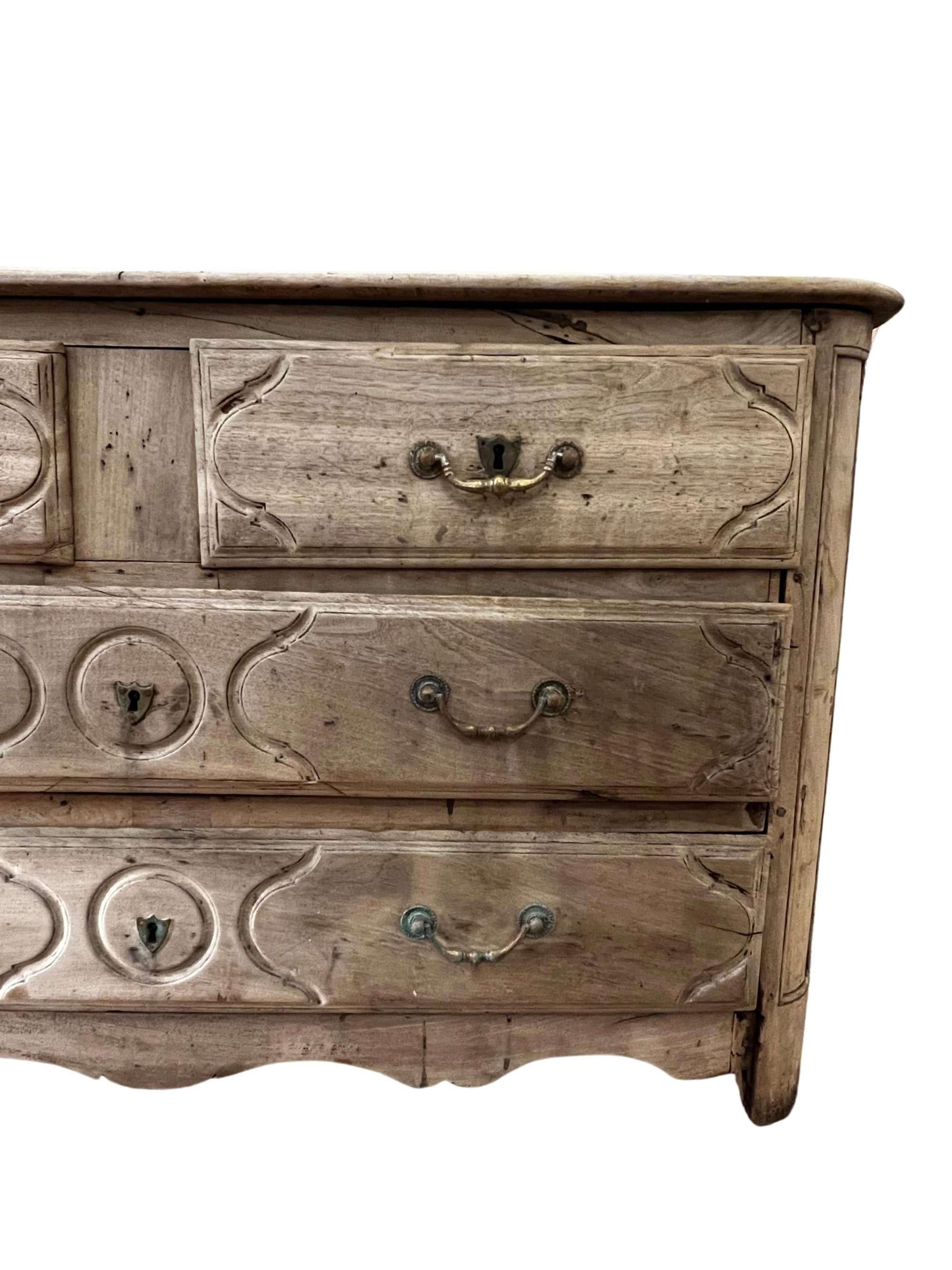 Un'affascinante commode in stile Luigi XV in finitura rovere sbiancato, con due cassetti piccoli e due cassetti grandi. La sua patina rustica è stata guadagnata con il passare del tempo, rendendolo un tesoro unico nel suo genere.