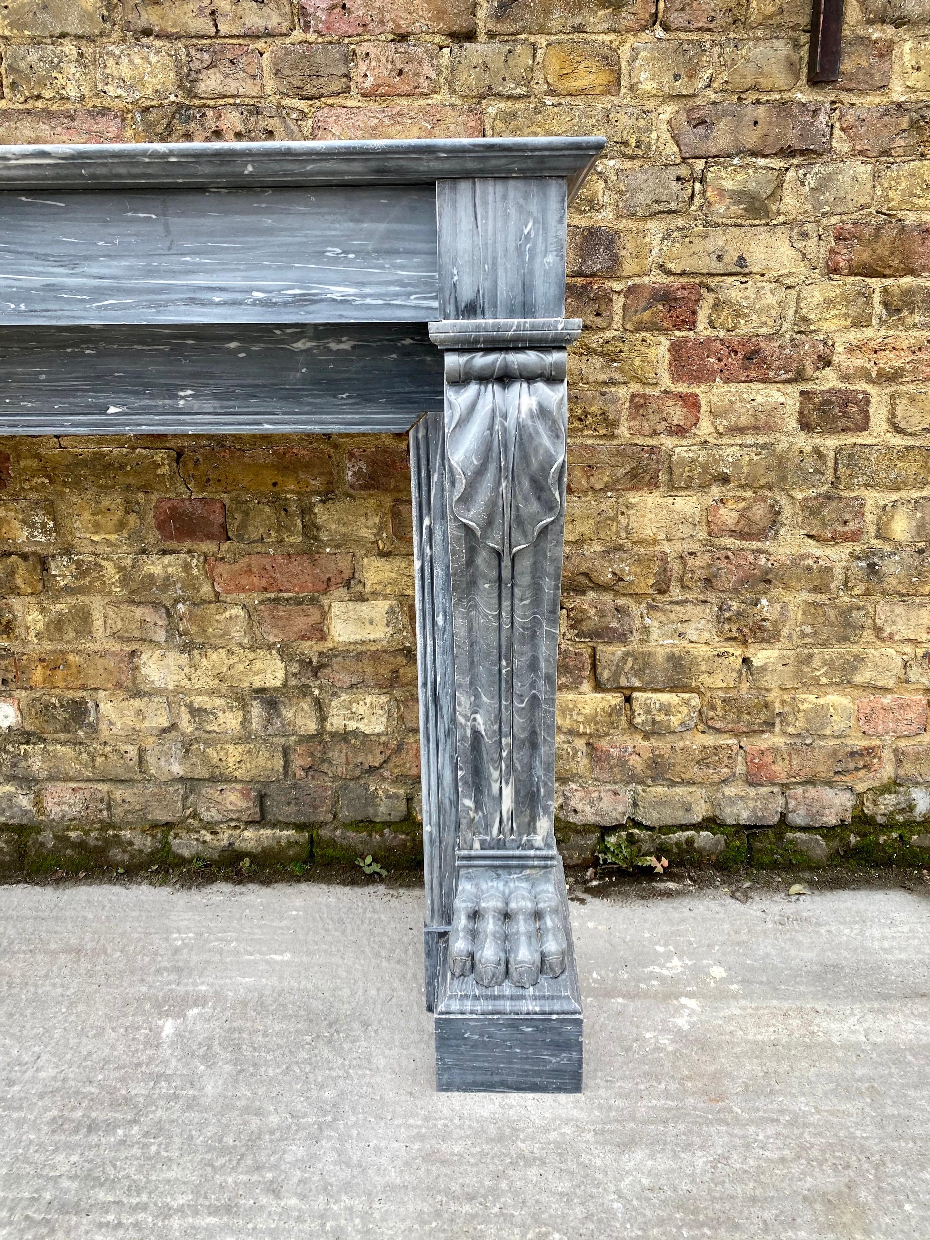 A late 18th century Louis XVI period fireplace in quality Bleu Turquin Bardiglio marble. The console jambs with scrolled and fluted front panels, having acanthus to top and well carved lions paw at the feet which are supported on substantial foot