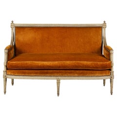 Un canapé Louis XVI tapissé de velours orange brûlé