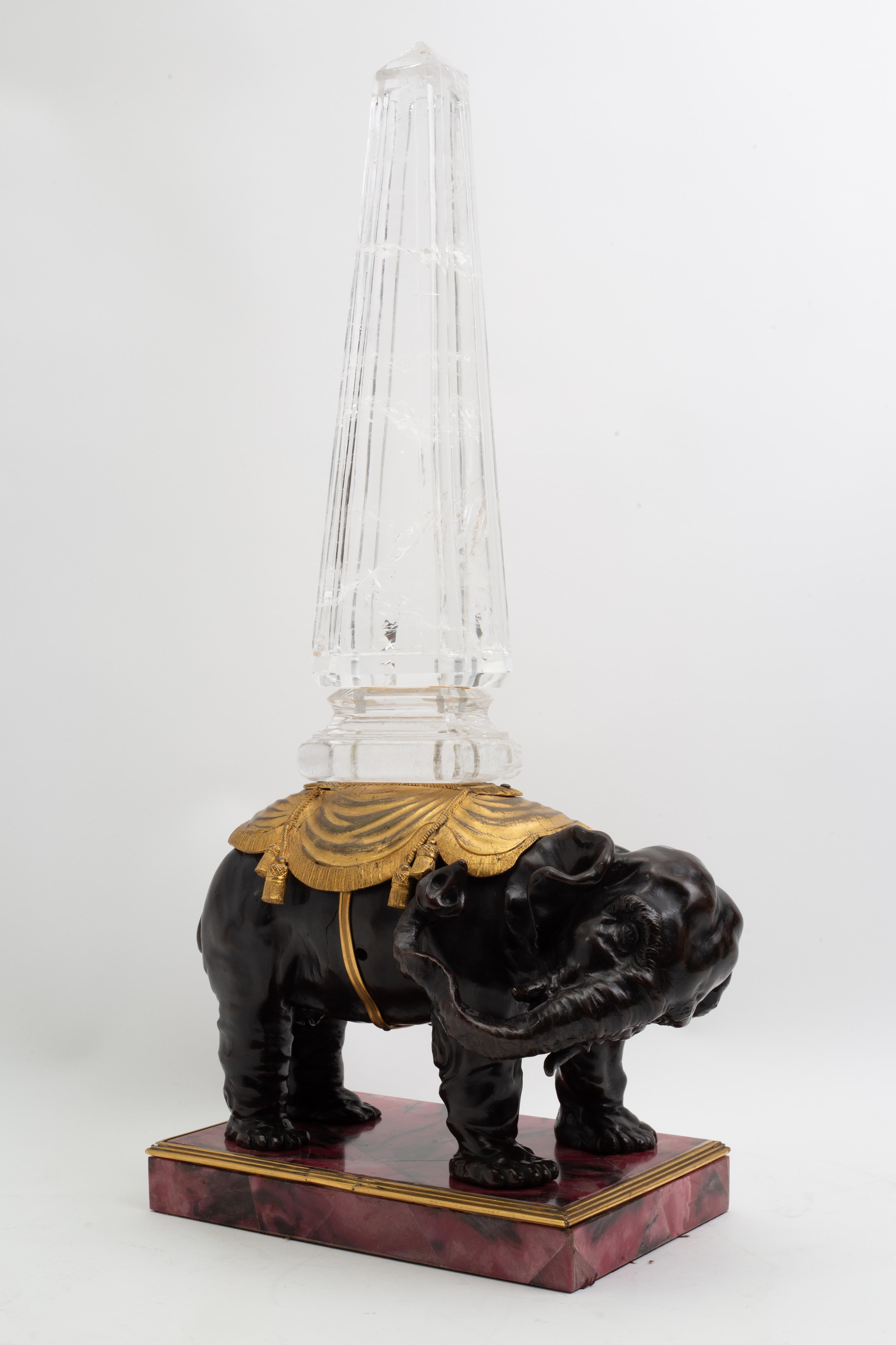 Grande modello di elefante in bronzo patinato e dorato in stile Luigi XVI, con obelisco in cristallo di rocca su una base di rodonite rosa

Questo imponente modello decorativo presenta un elefante fuso in bronzo patinato che sostiene un alto
