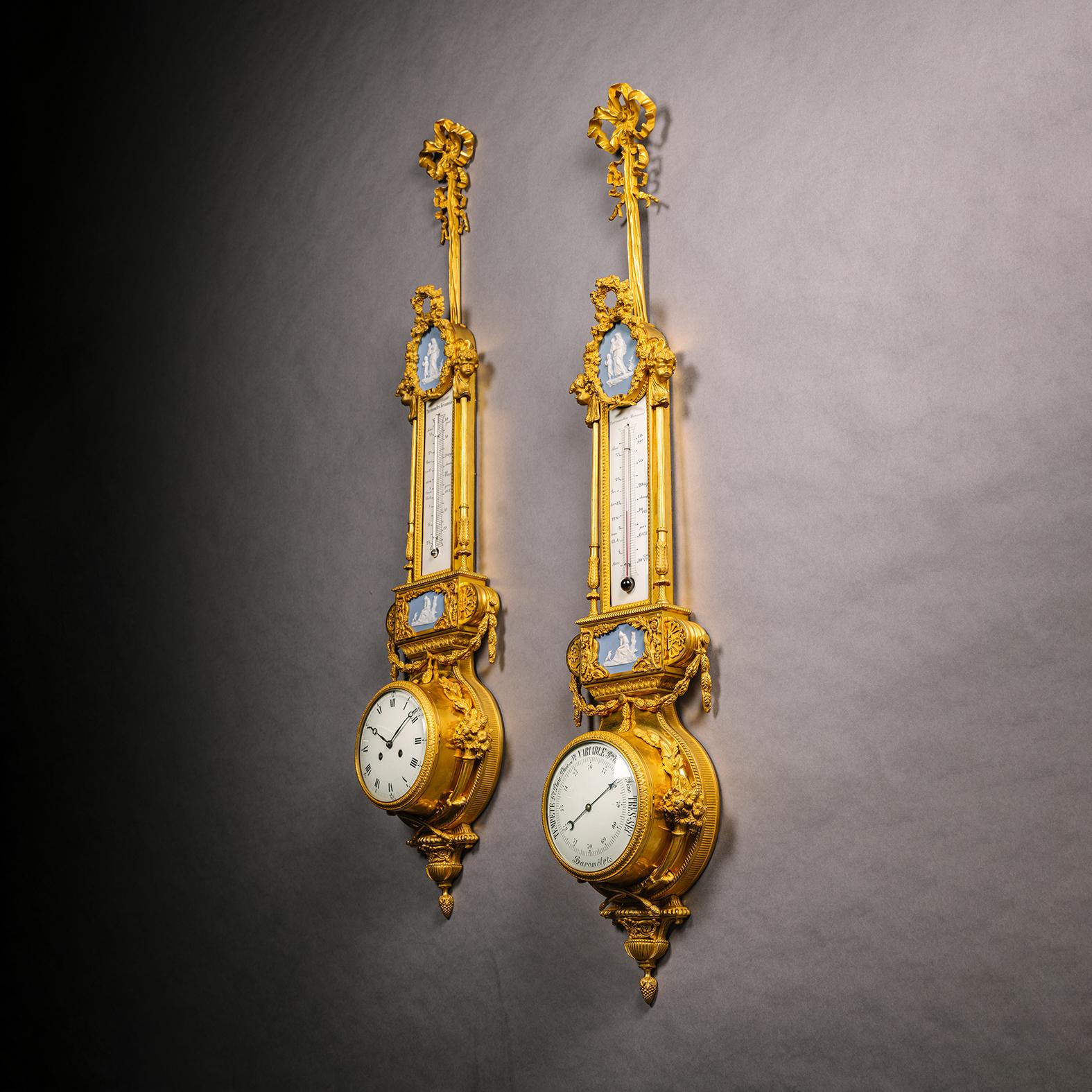 A Louis XVI Style Gilt-Bronze and Jasperware Mounted Cartel Clock and Companion Barometer, After the Model Attributed to Pierre Gouthière.

The clock and barometer each surmounted by accompanying thermometers, jasperware plaques and ribbon tied