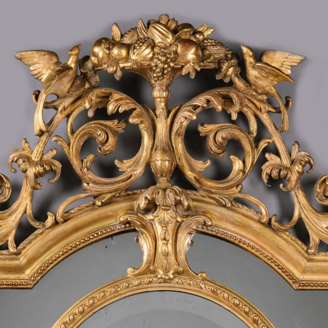 A fine Louis XVI style carved giltwood and gesso mirror.

The pierced scrolling crest surmounted by ho-ho birds flanking a basket of fruit over a shaped central bevelled mirror plate surrounded by further mirrored slips,

French, circa 1870.
 