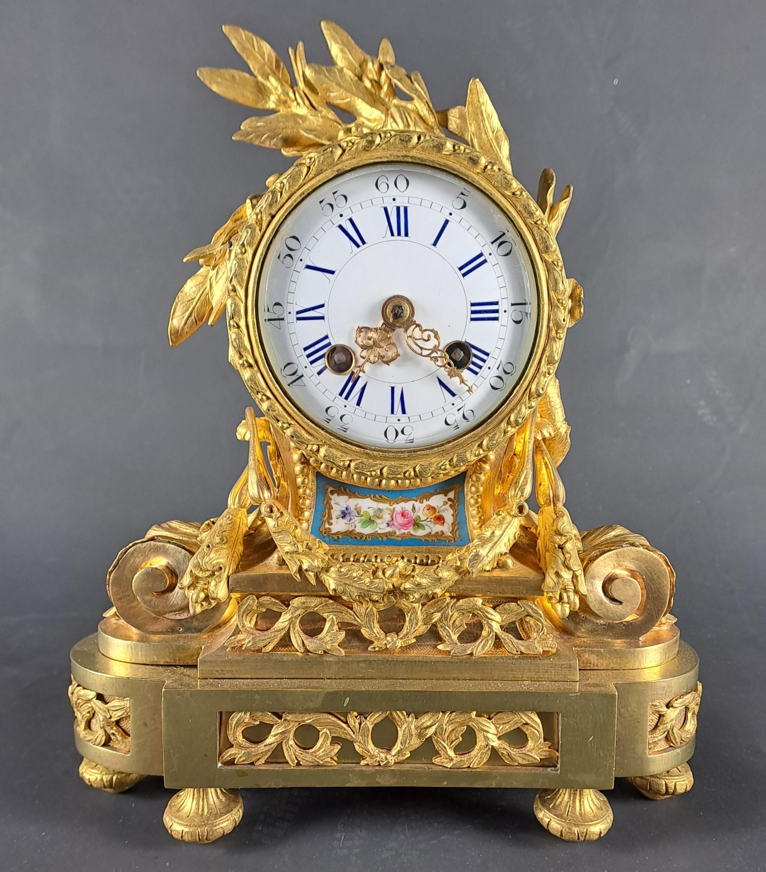 A Louis XVI style clock in gilt and chased bronze, richly decorated with branches, foliage and beaded friezes, featuring in its center a Sèvres porcelain plaque painted with polychrome flowers on a turquoise blue background and gilt trim.

French