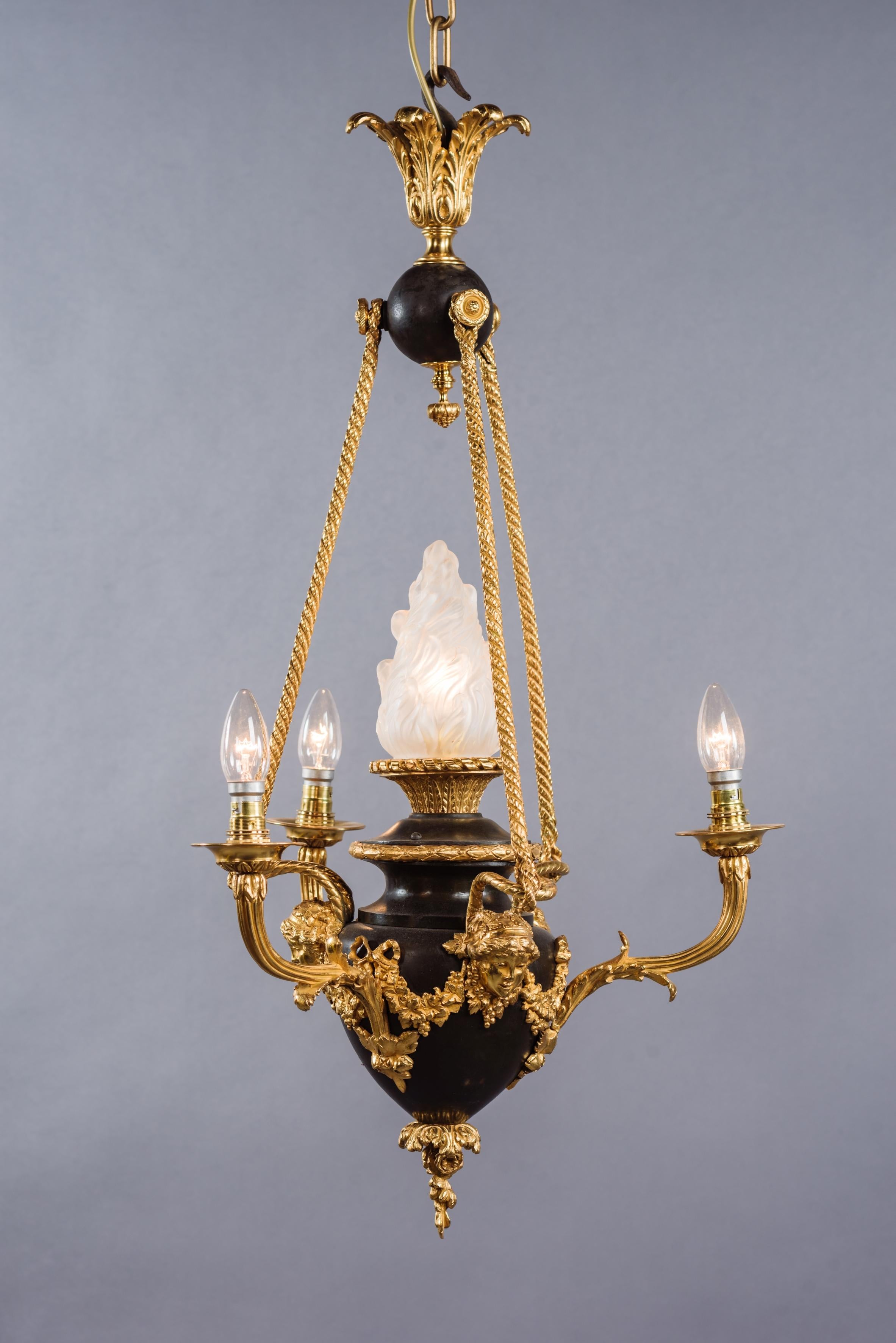 A Louis XVI style gilt and patinated bronze four-light chandelier.

French, circa 1900. 

The chandelier has a gilt-bronze acanthus cast corona above a patinated orb, with writhen suspensions rods suspending a patinated bronze urn embellished