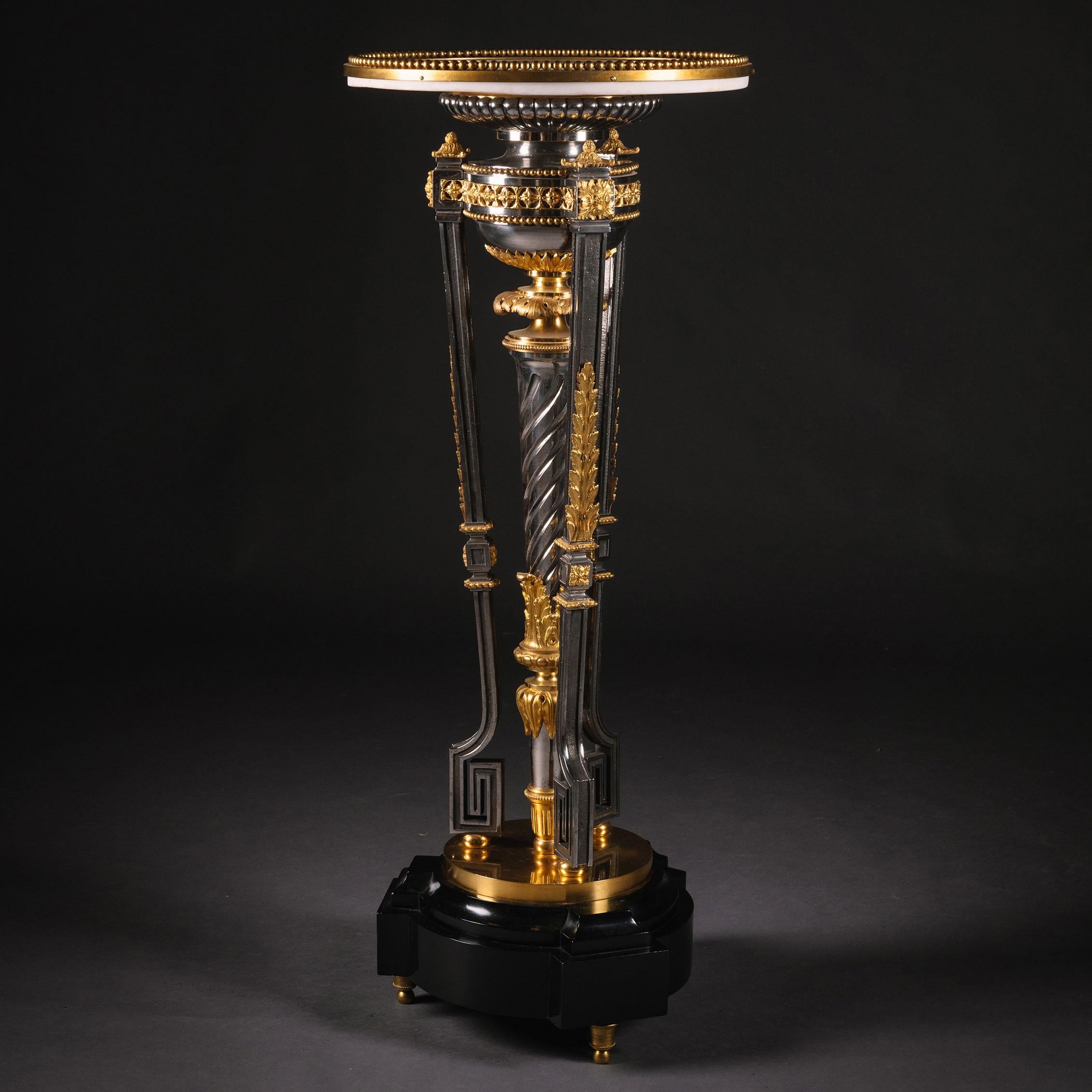 A Louis XVI style gilt-bronze and polished steel pedestal table.

The circular white marble top with bead cast surround, on athenienne tripod support with central spirally-fluted stem, on an ebonised base raised on toupie feet.

France, Circa 1870.