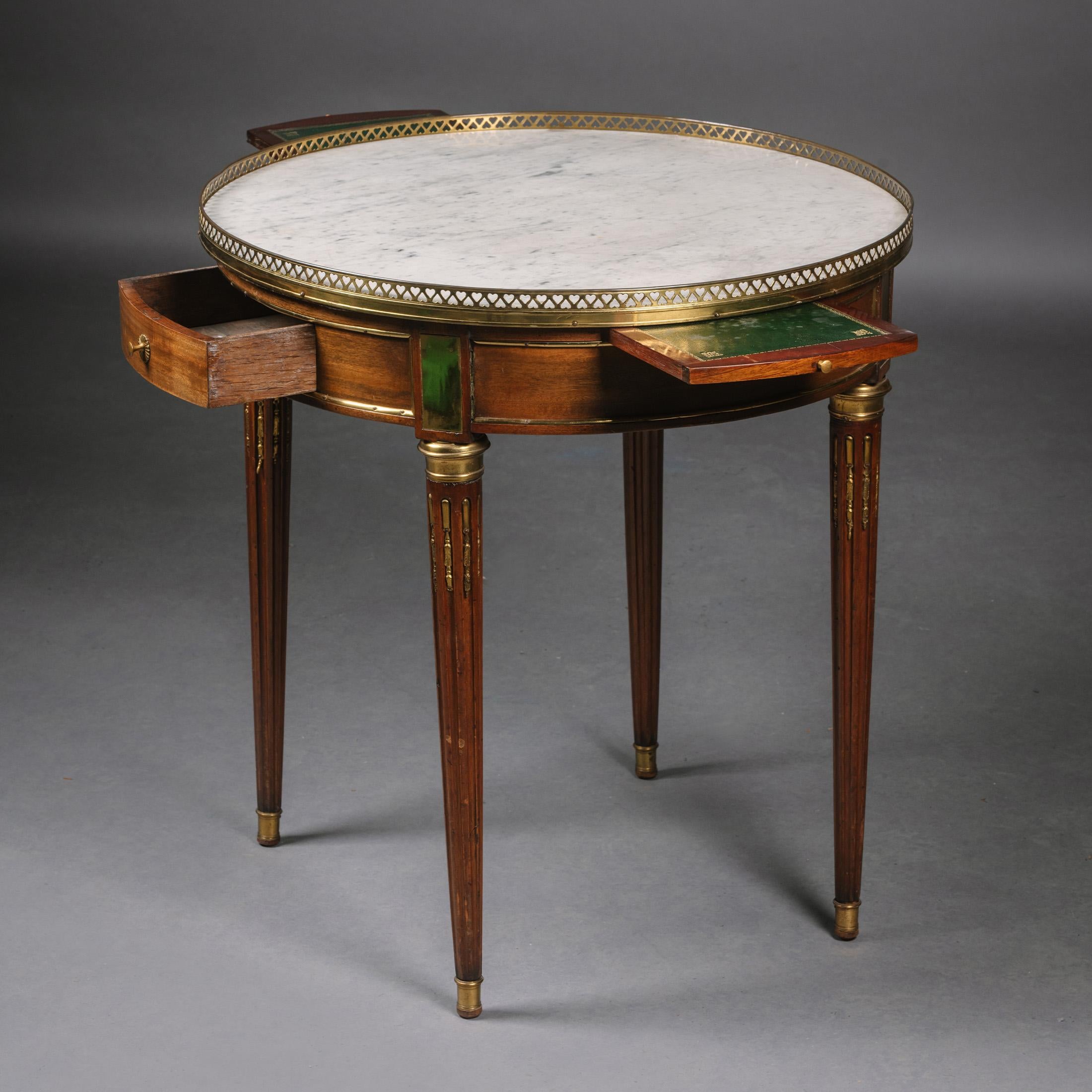 A Louis XVI Style Gilt-Bronze Mounted Mahogany Gueridon.

This charming occasional table is of an especially useful Size. It has a white marble top with a brass gallery pierced with heart-shaped holes, above a small frieze drawer flanked to each