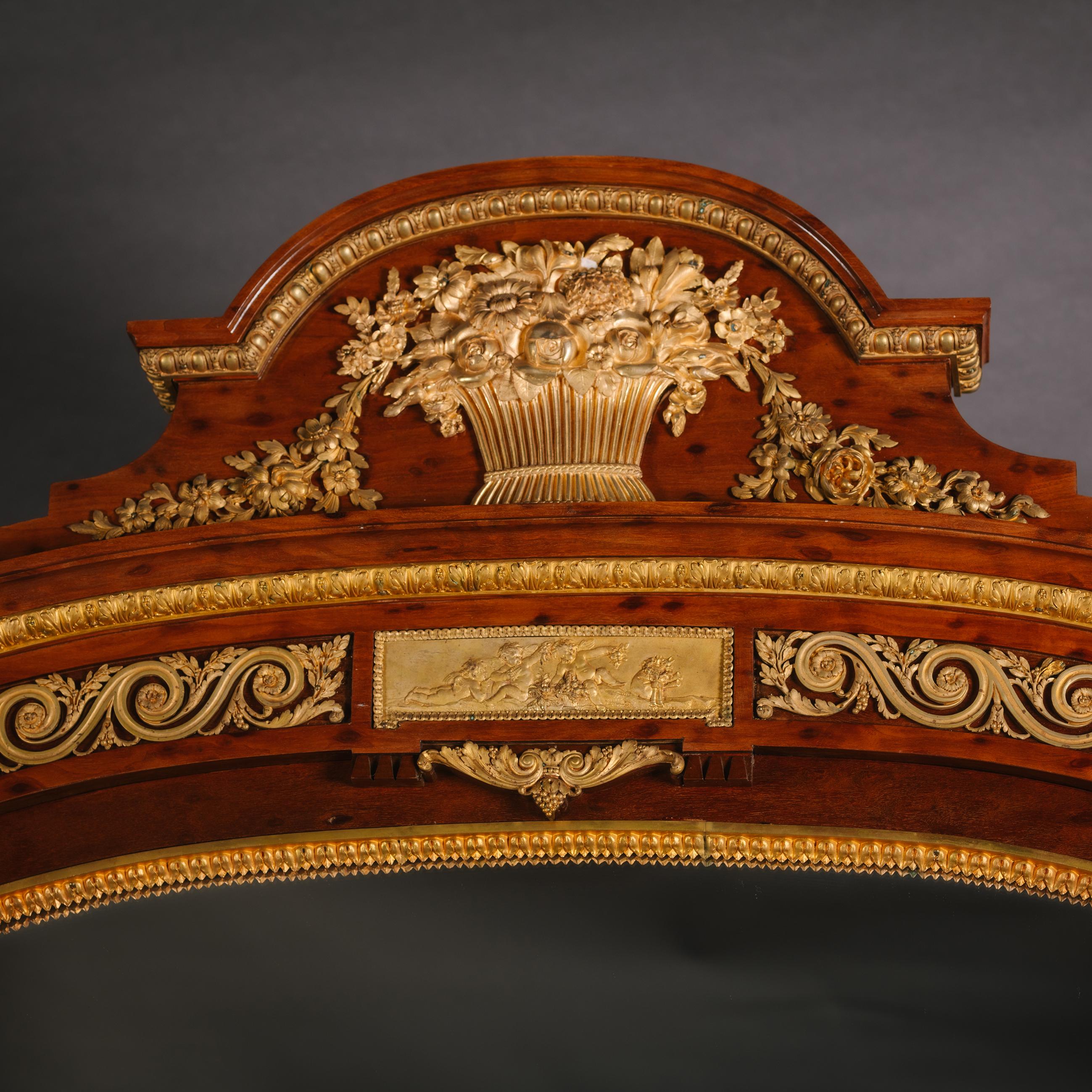 A Large and Very Fine Louis XVI Style Gilt-Bronze Mounted Mahogany Mirror. 

This fine 'plum pudding' mahogany mirror has an arched pediment centred by a gilt-bronze basket issuing flowers above a frieze of viruvian scroll centred by a tablet