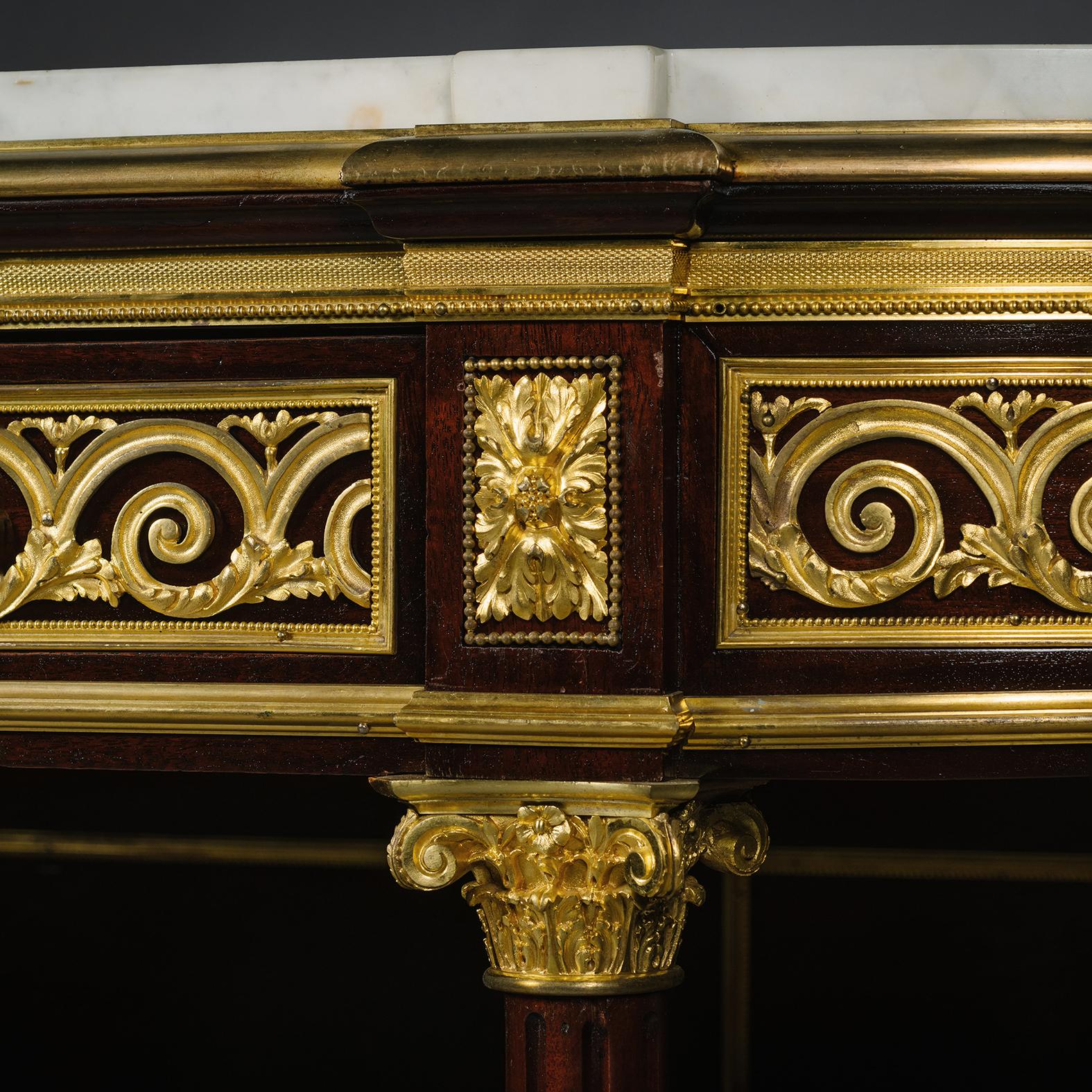 A Fine Louis XVI Style Gilt-Bronze Mounted Marble Top Mahogany Three-Tier Console Desserte. 

The moulded ‘D’ – shaped veined white marble top above a gilt-bronze viruvian scroll and acanthus mounted frieze with a central fitted drawer, on fluted