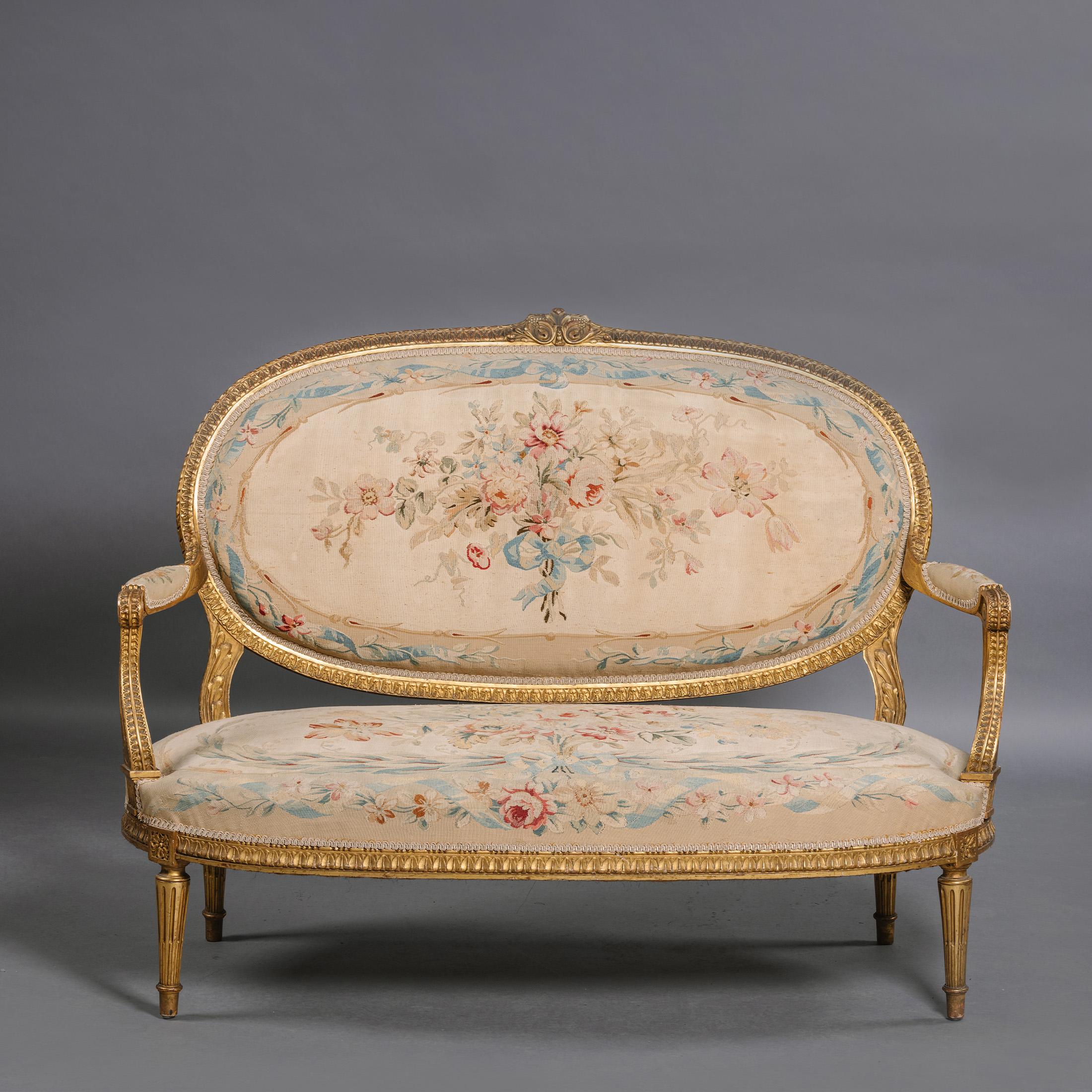 Suite de salon en bois doré et tapisserie d'Aubusson de style Louis XVI, composée de cinq pièces.

Cet ensemble de meubles d'assise comprend quatre fauteuils ouverts aux proportions généreuses et un canapé, en suite. Chacune d'entre elles possède un