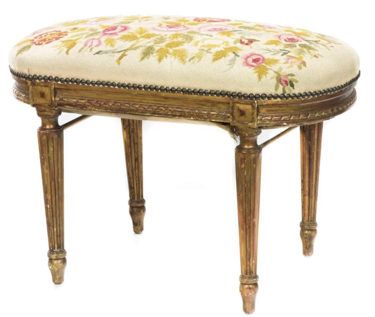 A Louis XVI style giltwood tabouret, late 19th century, having a needlework top, above ribbon carved and fluted legs. Wonderful old warm patina to the surface.