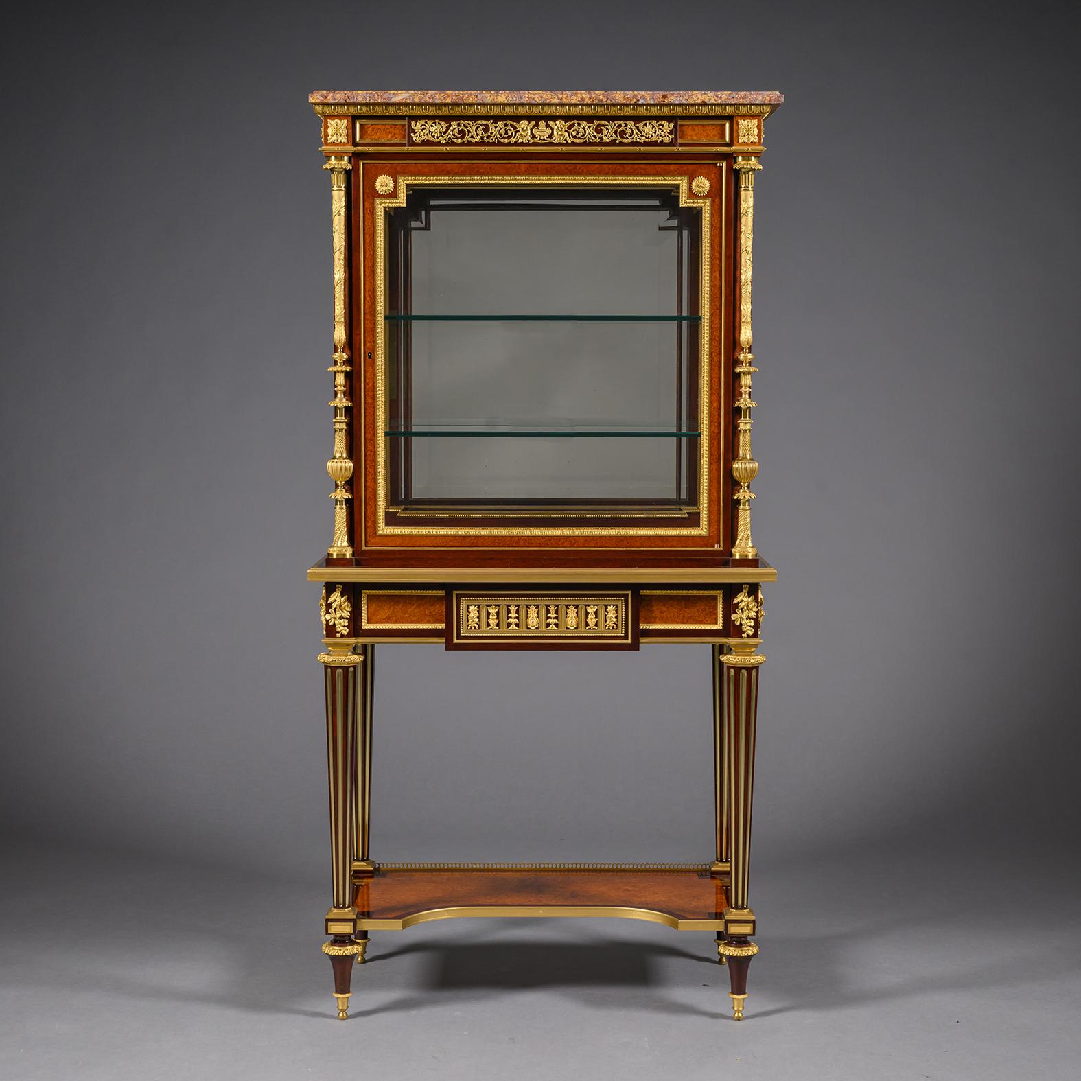 A Fine Louis XVI Style Gilt-Bronze Mounted Mahogany and Amboyna Vitrine Cabinet-On-Stand, Attributed to Henry Dasson.

This fine vitrine cabinet has an upper section with a shaped rectangular brocatelle jaune d'Espagne marble top, above an egg and