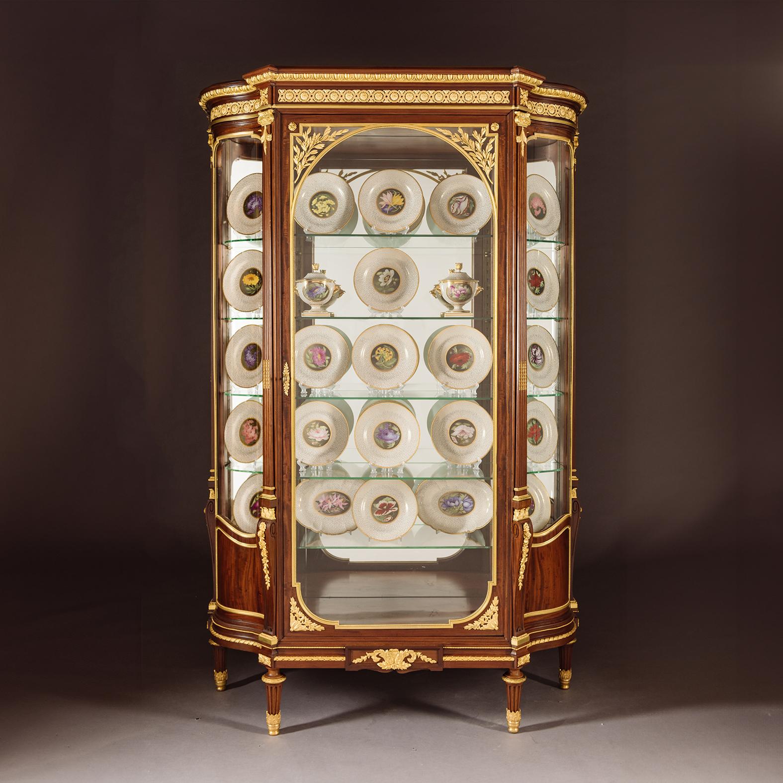 Grande e rara vetrinetta in mogano montata in bronzo dorato in stile Luigi XVI, opera di François Linke. Parigi.

Il fregio a frontone con montature in bronzo dorato a forma di fiore. La porta centrale vetrata con rami di alloro agli angoli