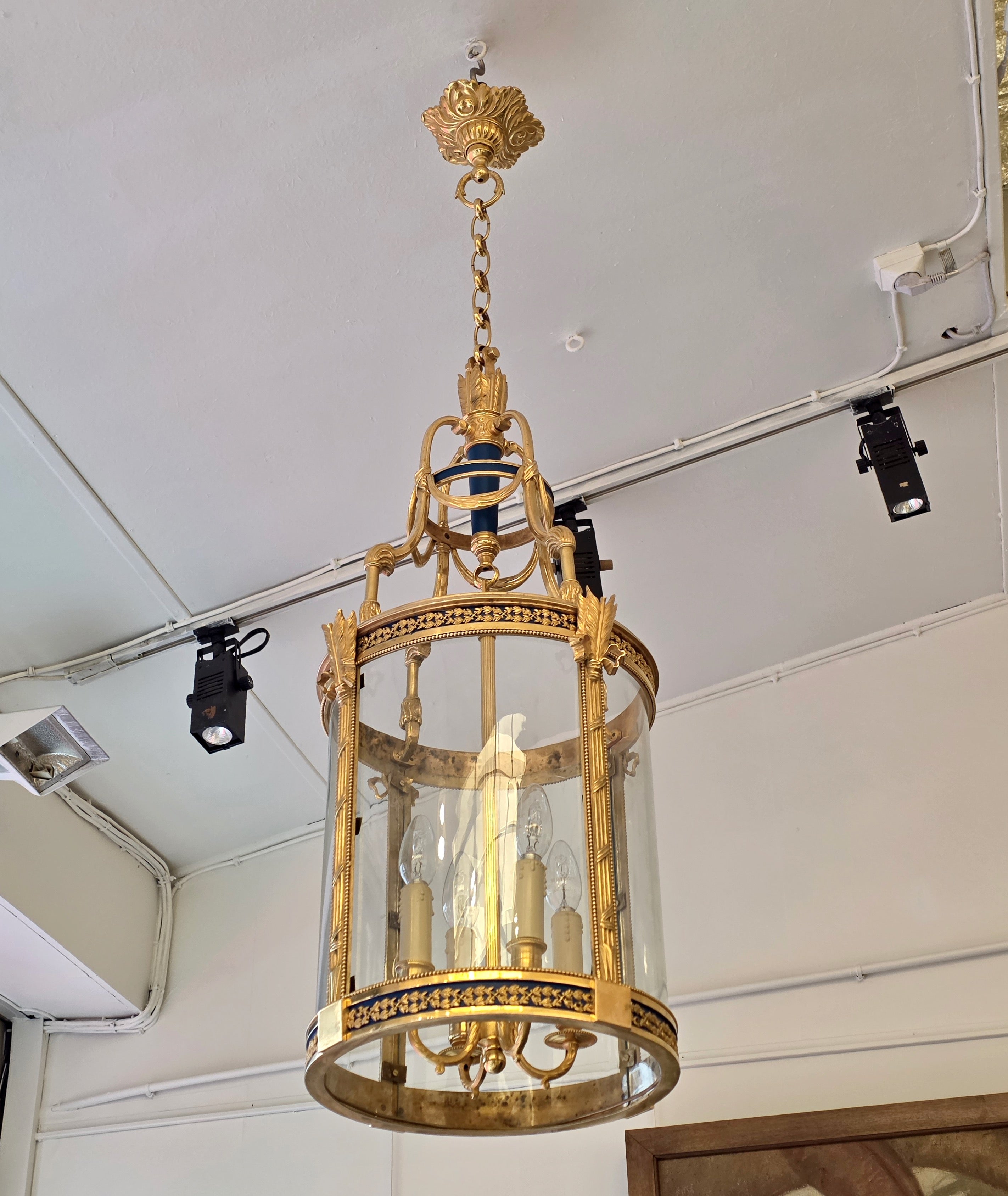 A Louis XVI  Style Patinated and Gilt Bronze Four Light Hall Lantern

Circular lantern in chased, gilded and blue-patinated bronze, the shaft decorated with a quiver motif adorned with drapery, the upper and lower borders decorated with a frieze of