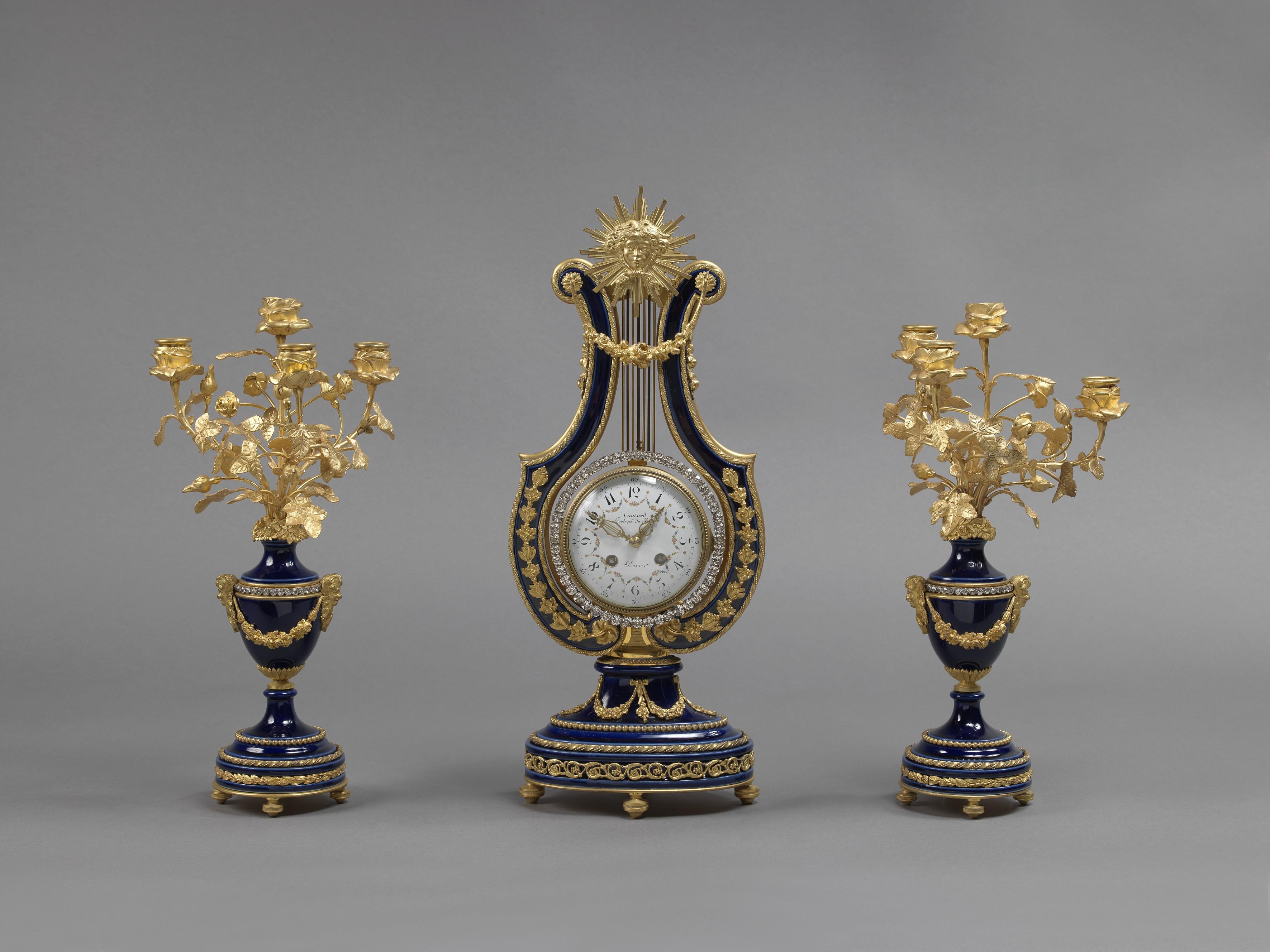 A fine Louis XVI style cobalt blue porcelain and gilt-bronze lyre clock garniture, with jewel set pendulum. 

French, circa 1900.

The candelabra bearing a paper label to the underside for ‘CAMUS, S,R, Saint Ambroise, PARIS’.

Clock: