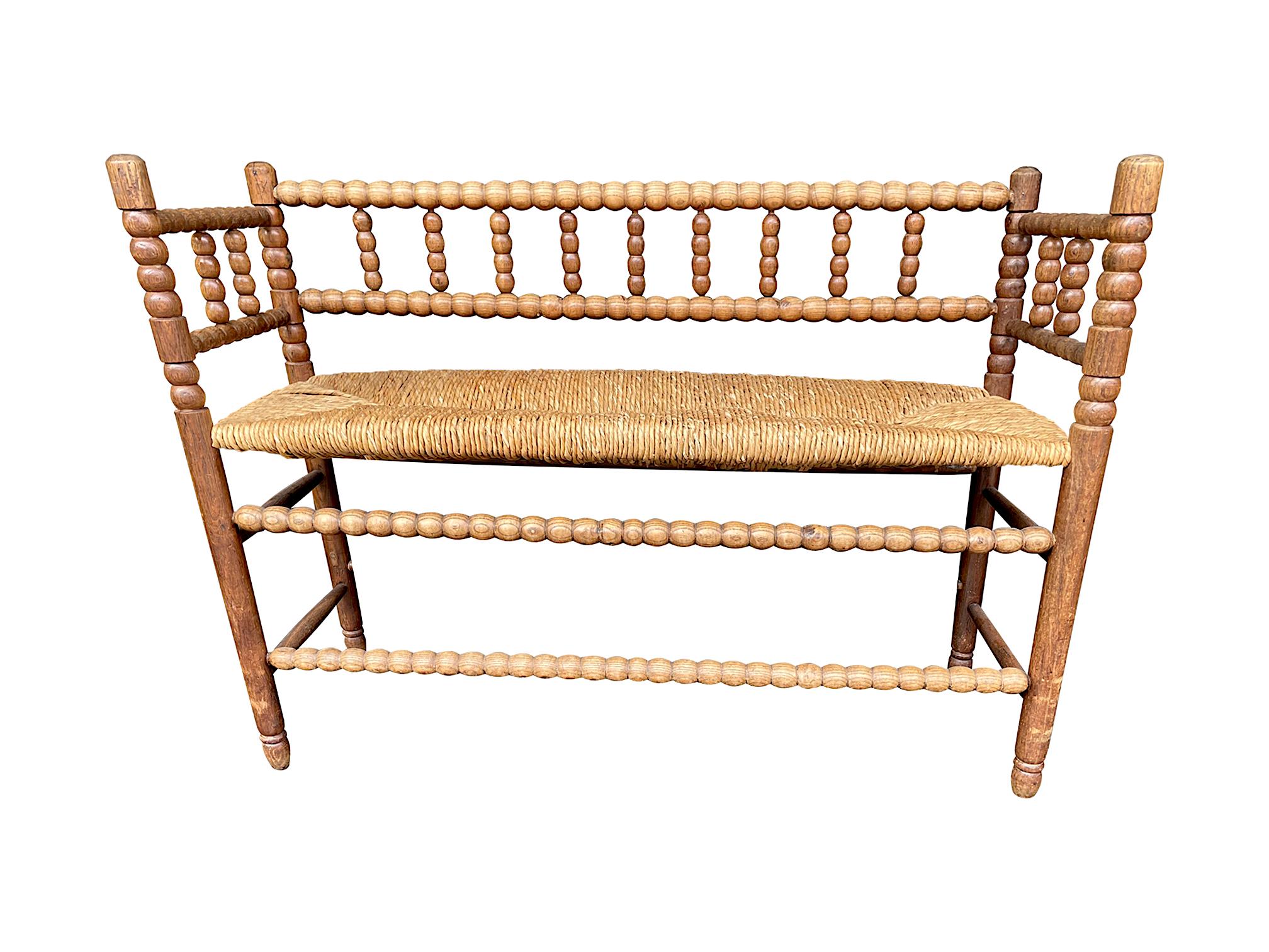 A lovely 1890s English oak and elm bobbin bench seat with original rush woven seat with lovely patina and grain and in good structural condition.