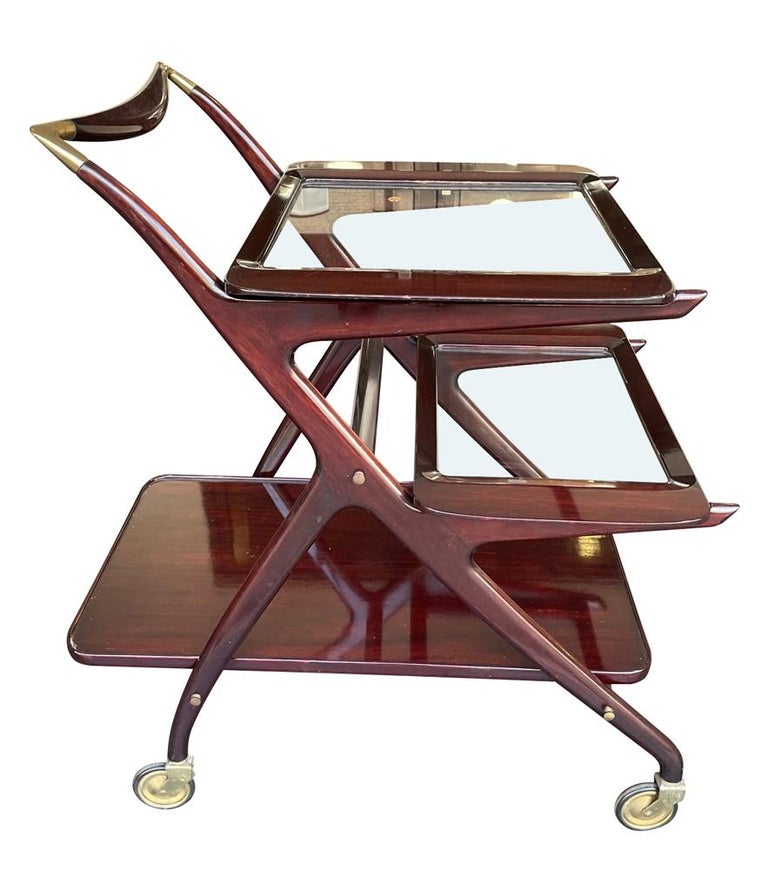 A 1950s Cesare Lacca bart cart trolley in rich lacquered mahogany with removable glass trays with brass detailing and orignal brass castors, for Italian company Cassina.