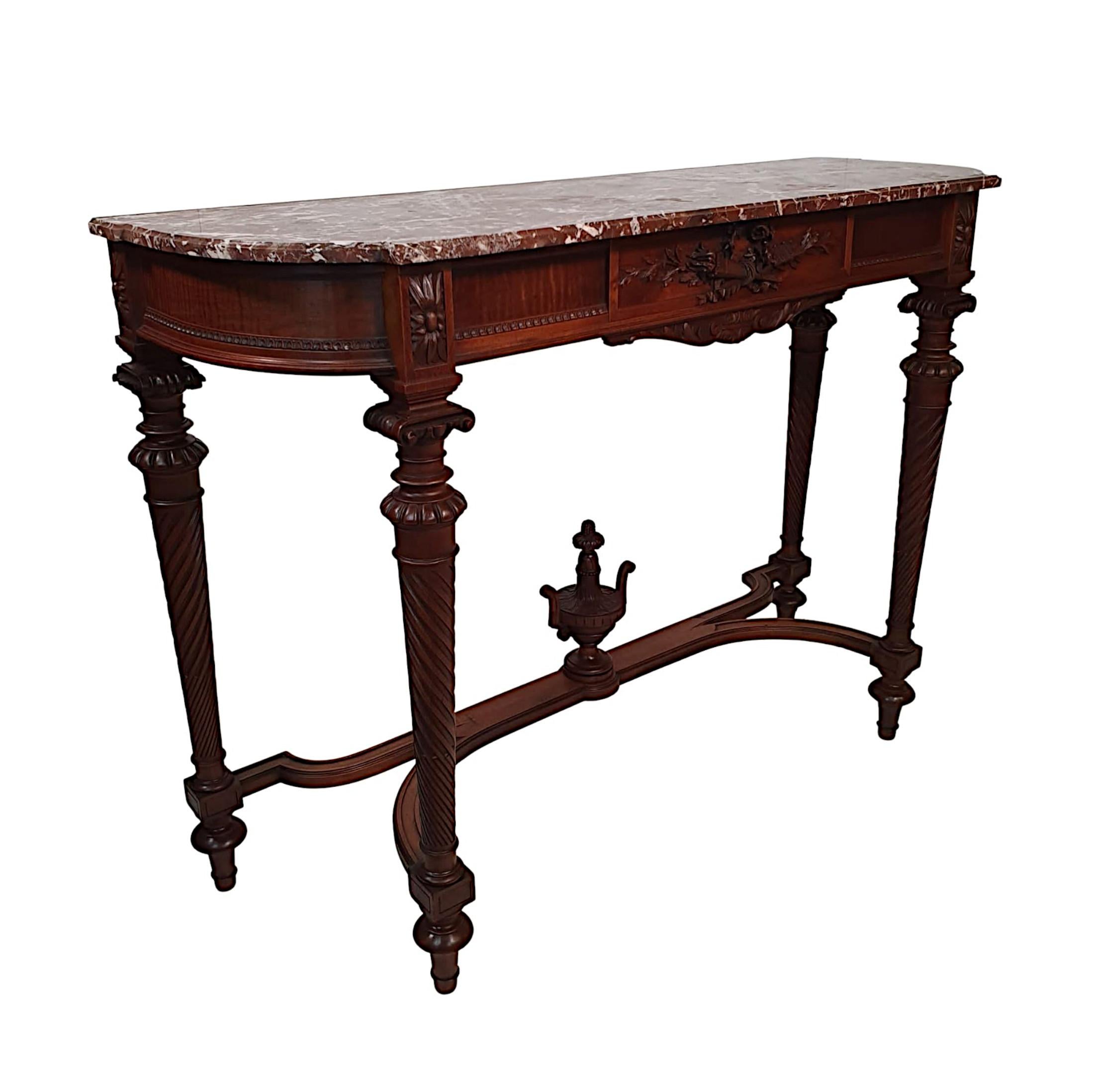 A lovely quality early 20th Century marble top mahogany console table. The shaped and moulded Rosso Levante marble top raised over panelled frieze with applied flowerhead paterae, egg and dart detail. The central panel with Neoclassical motifs of