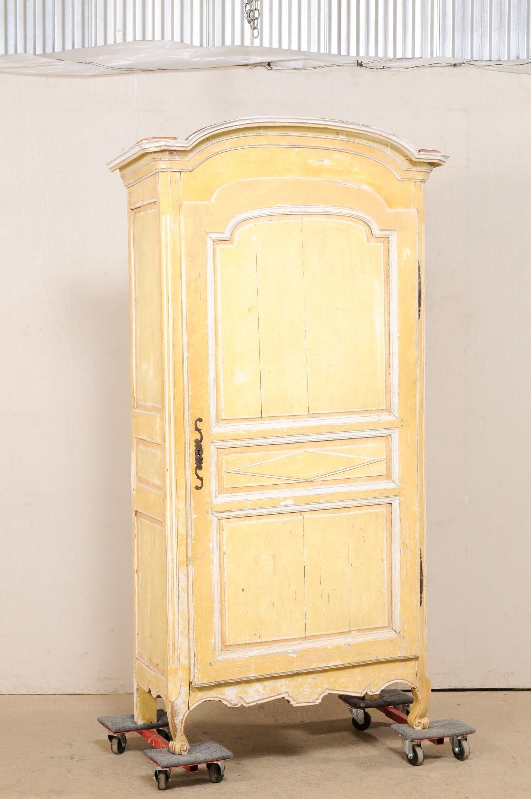 A tall French single-door cabinet, with its original paint, from the 19th century. This antique cupboard cabinet from France features a beautifully molded and elongated arch shaped cornice which rests upon a tall case that is fitted with a single