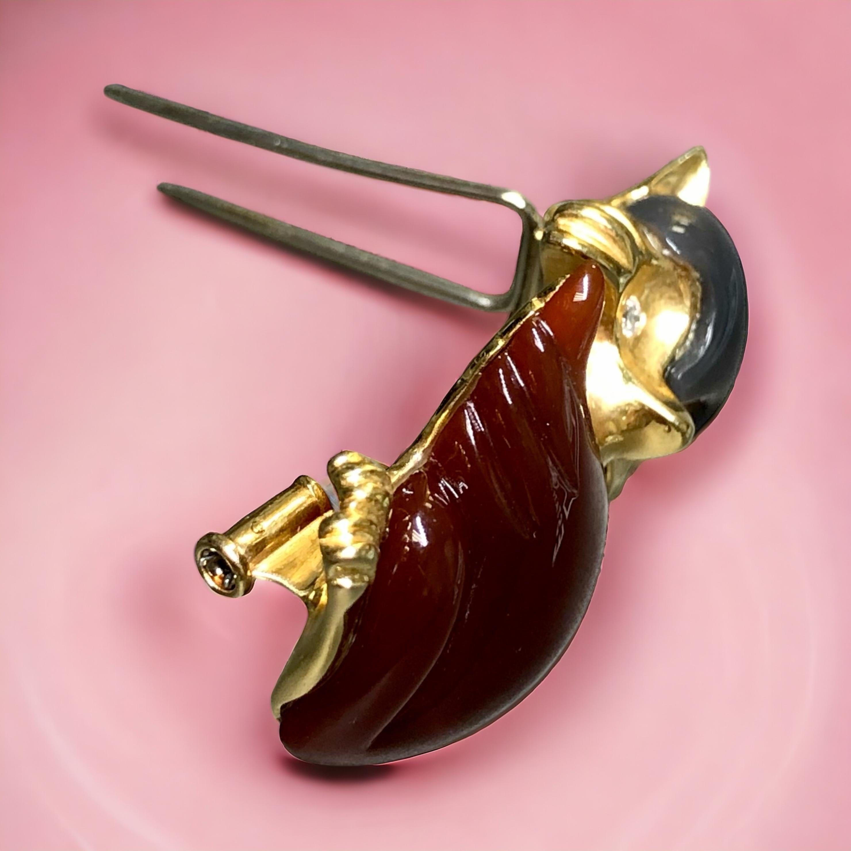 
A lovely little fox brooch hand crafted in 18K yellow gold and set with carved carnelian and gray agate and finished with .06cttw diamonds for the eyes. There is a designer stamp on the rear, but we are unable to attribute it to anyone specific. A