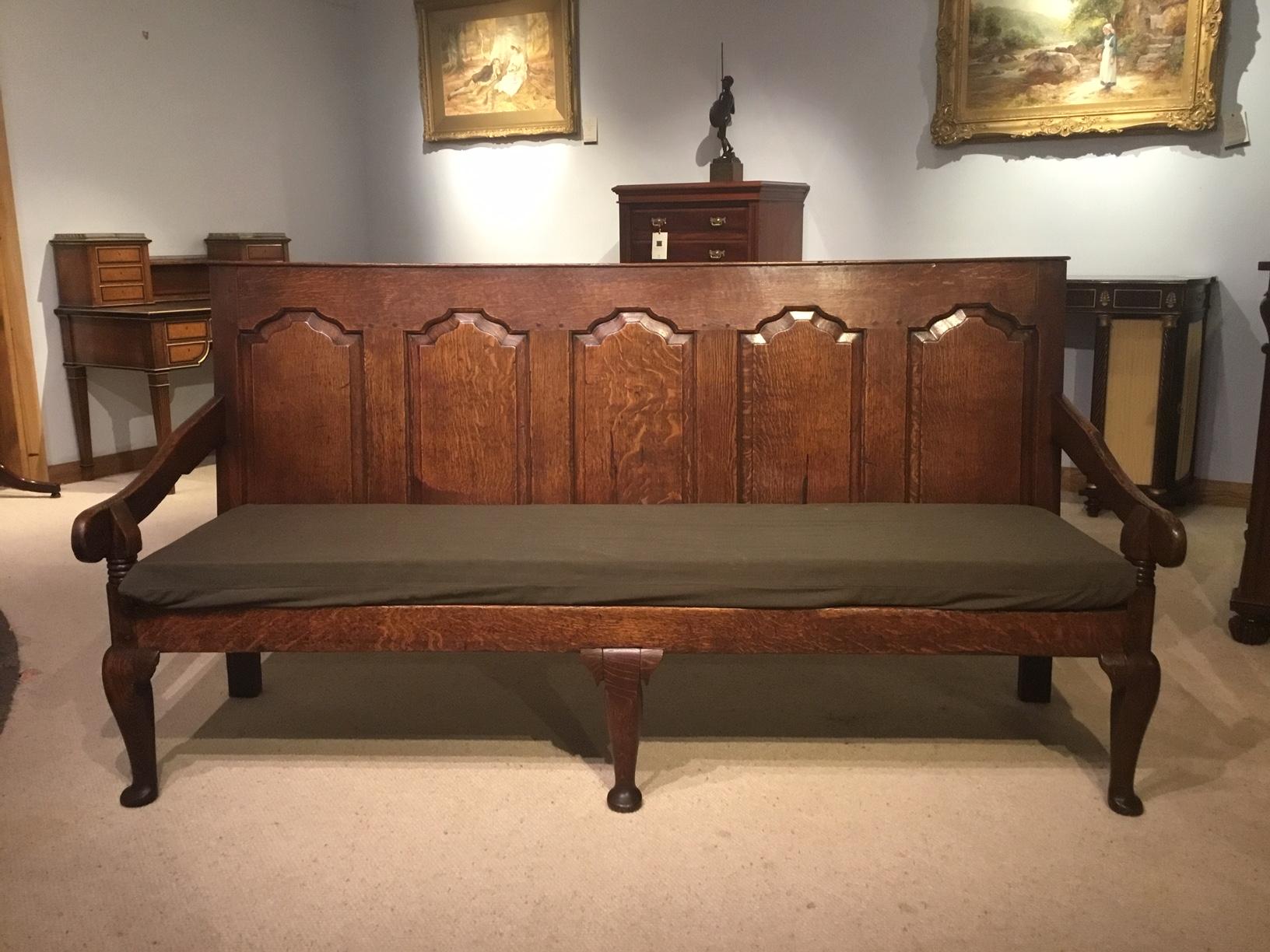 A lovely oak 18th century original five panel settle. The oak back has five wonderful fielded and shaped panels with pegged construction throughout. With a removable cushion, shaped open arms and supported on three cabriole supports with pad feet