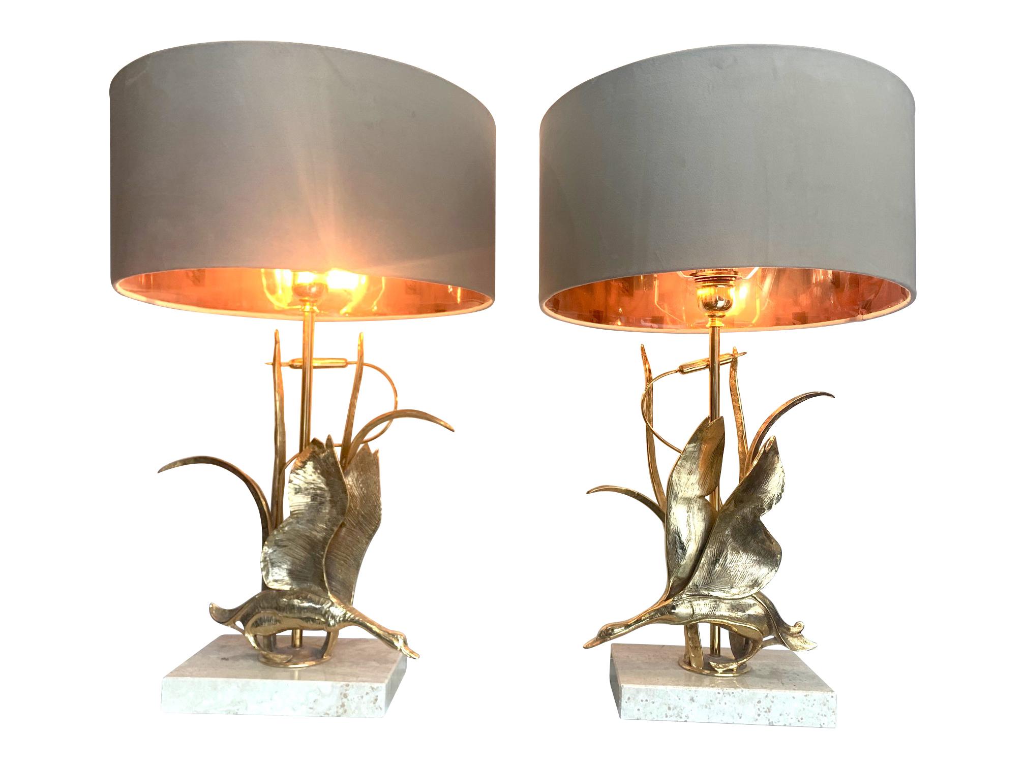 A lovely pair of 1970s brass duck lamps by Lanciotto. Galeotti for Italian company L'Originale each with a brass duck flying out of the bullrushes, mounted on travertine bases with a single fitting in each. Re wired with antique gold cord flex and